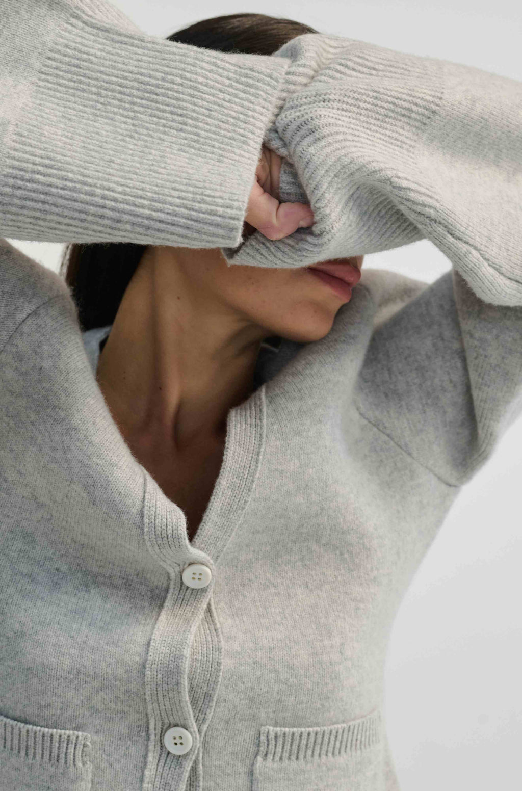 Person wearing a light gray sweater with a neutral background