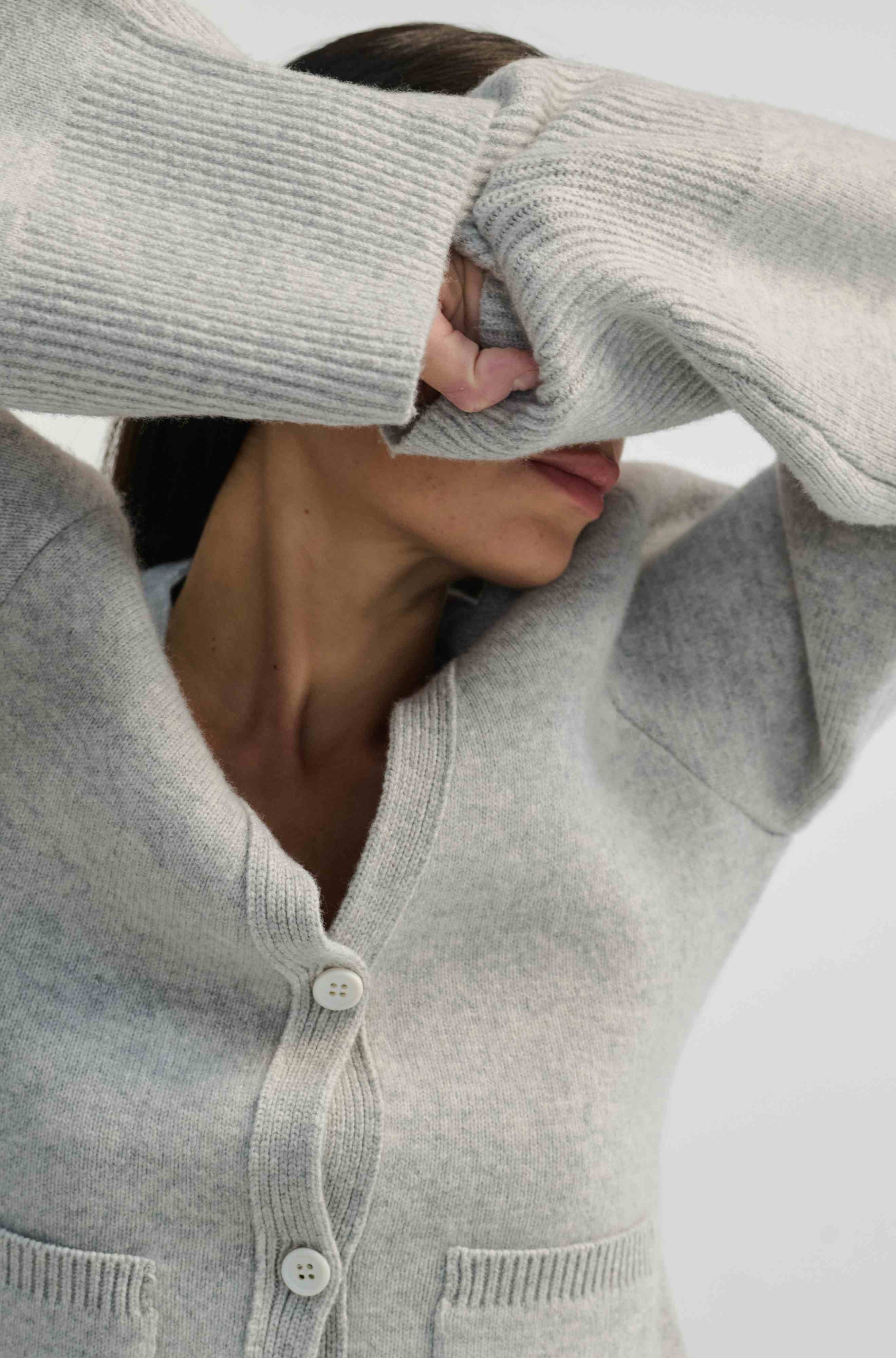 Person wearing a light gray sweater with a neutral background