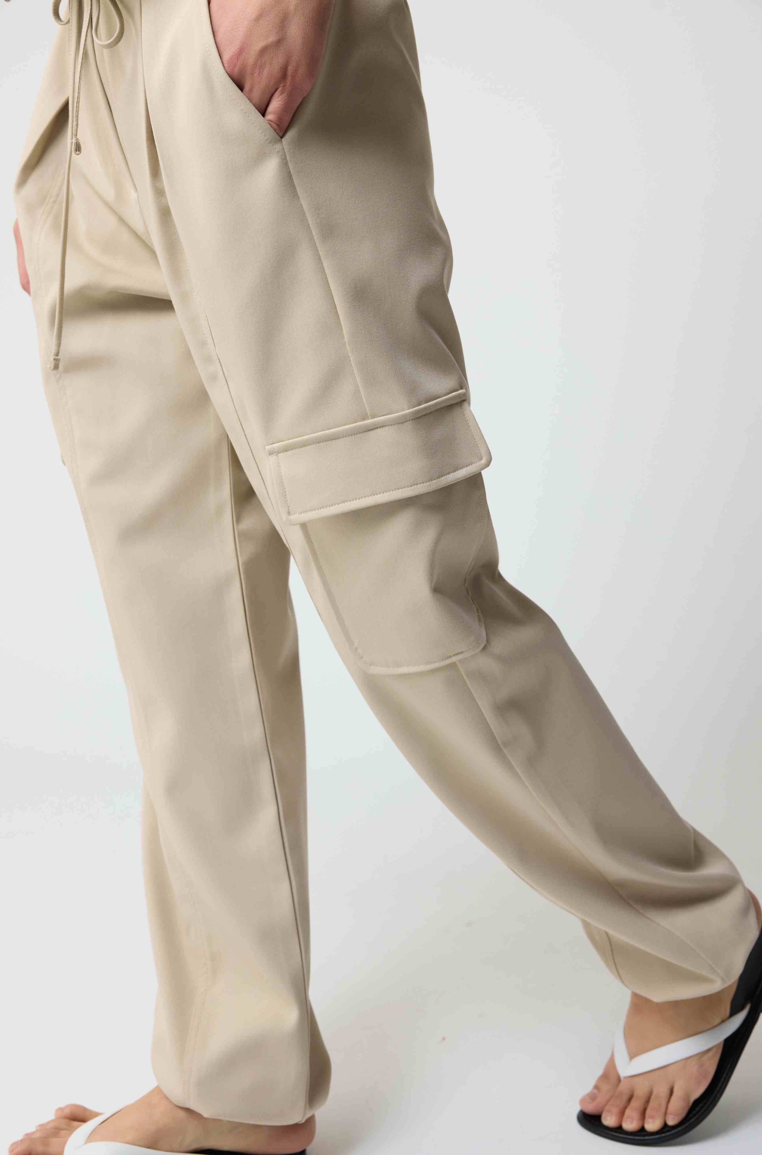 Woman wearing beige cargo pants on a light grey background