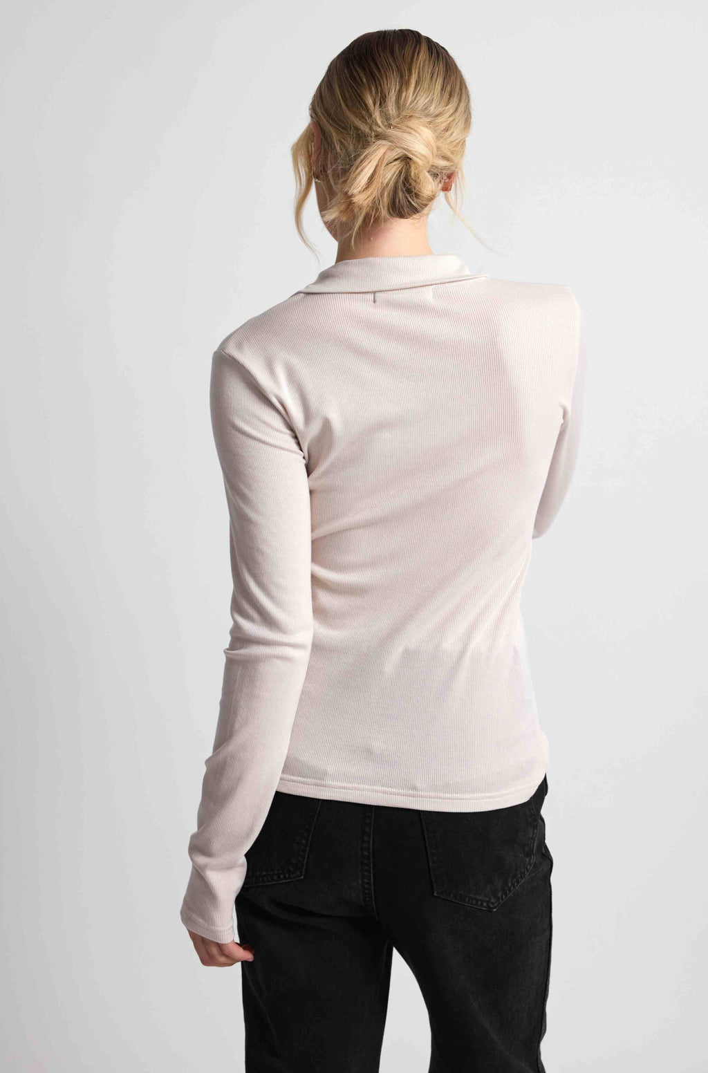 Woman wearing a pink button up top with black bottoms on a light grey background