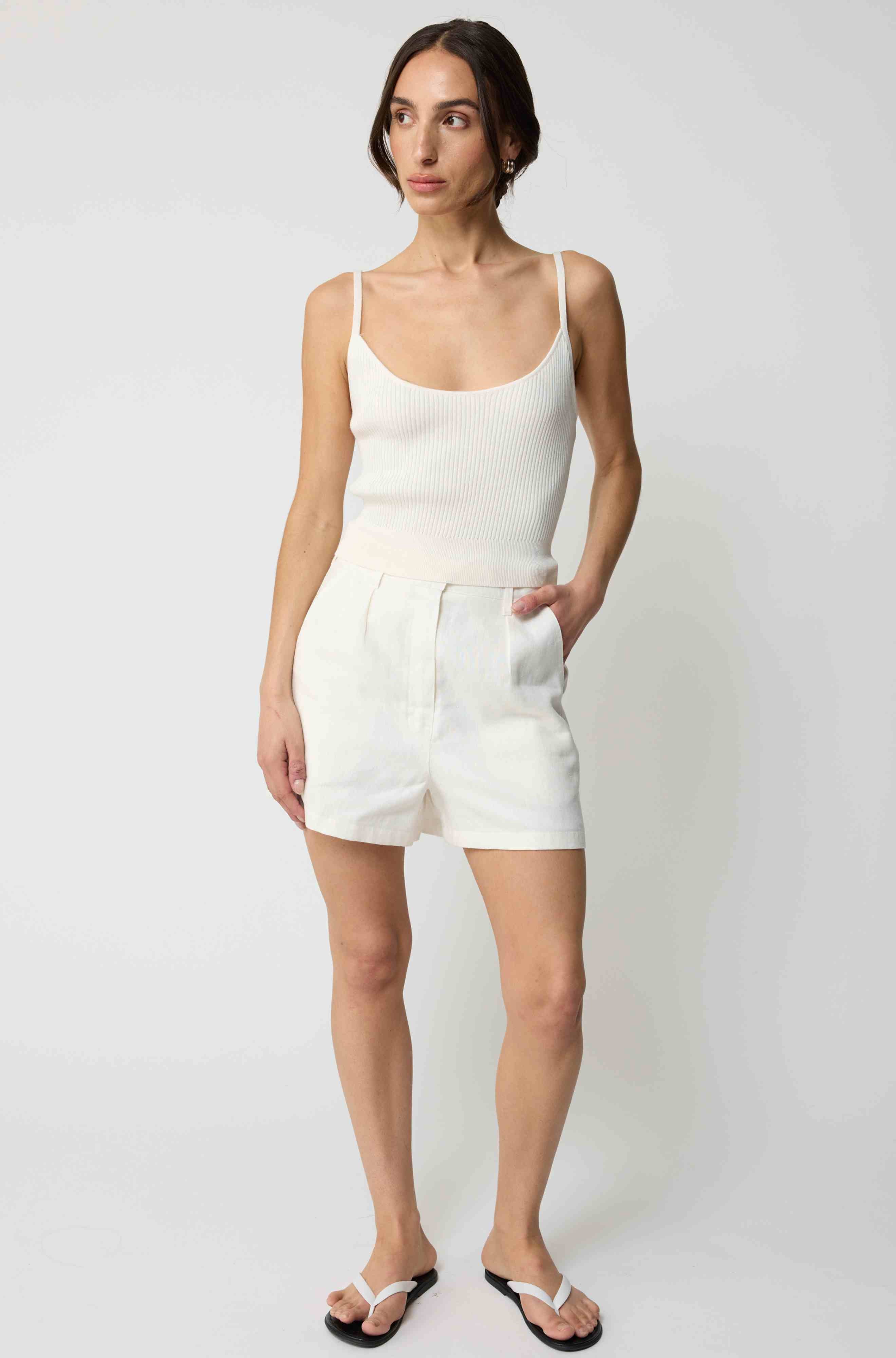 Woman wearing a white tank top and white linen shorts
