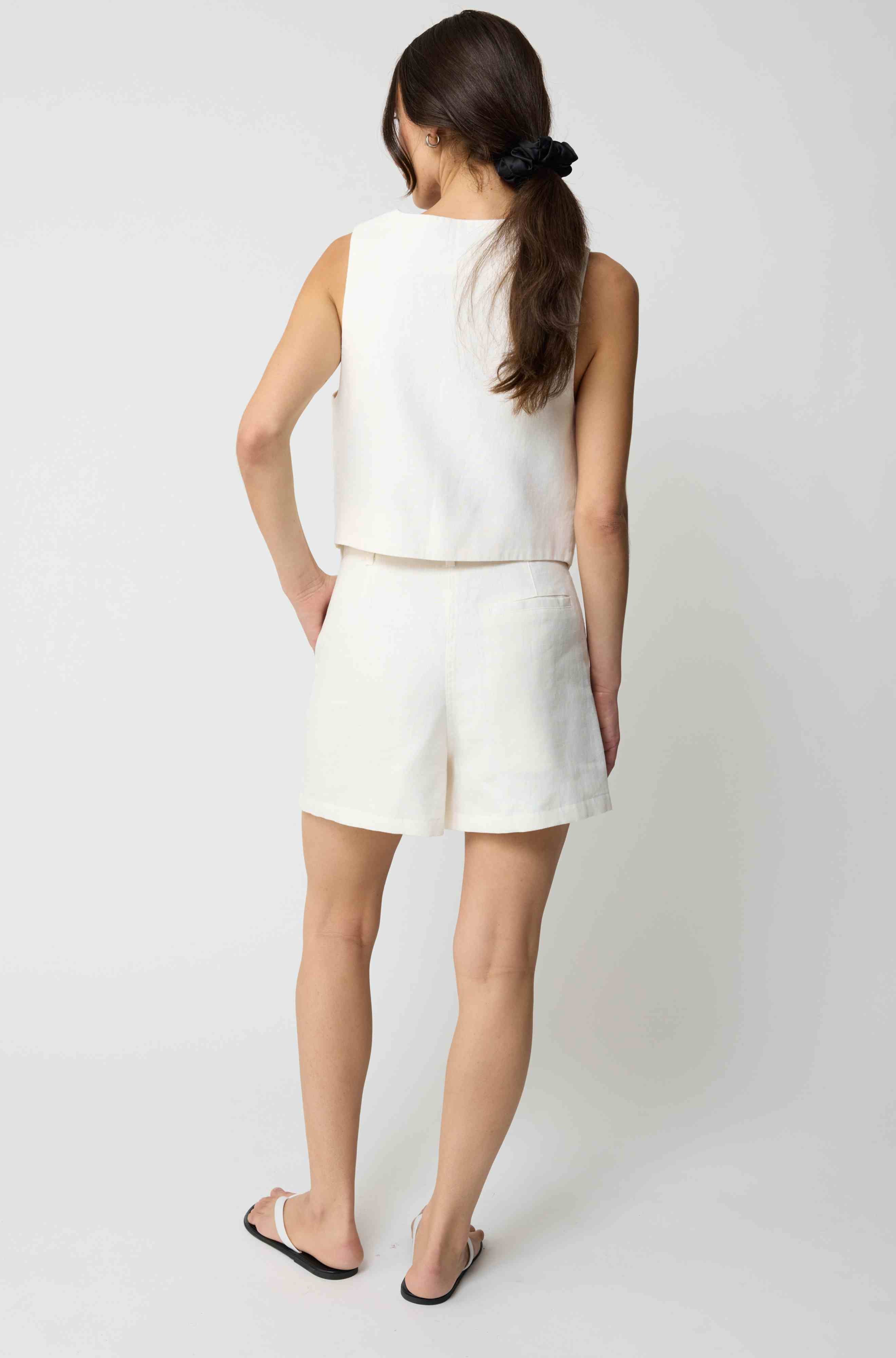 Woman wearing a white tencel vest and white linen shorts