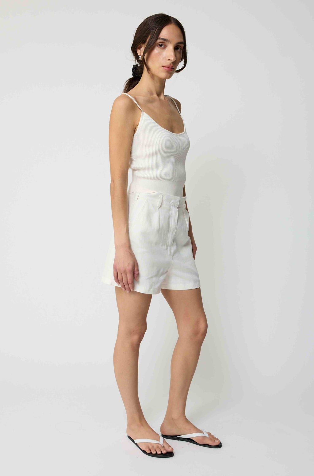 Woman wearing a white tank top and white linen shorts