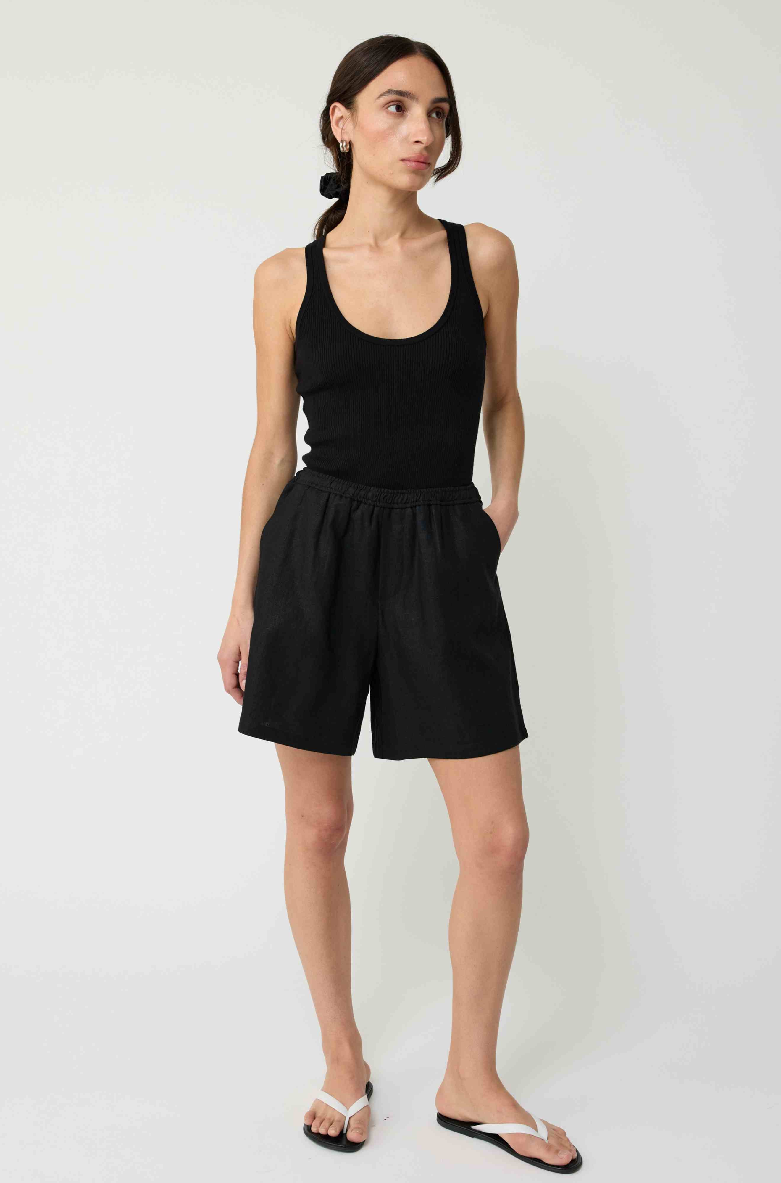 Woman wearing a black tank top and black linen shorts