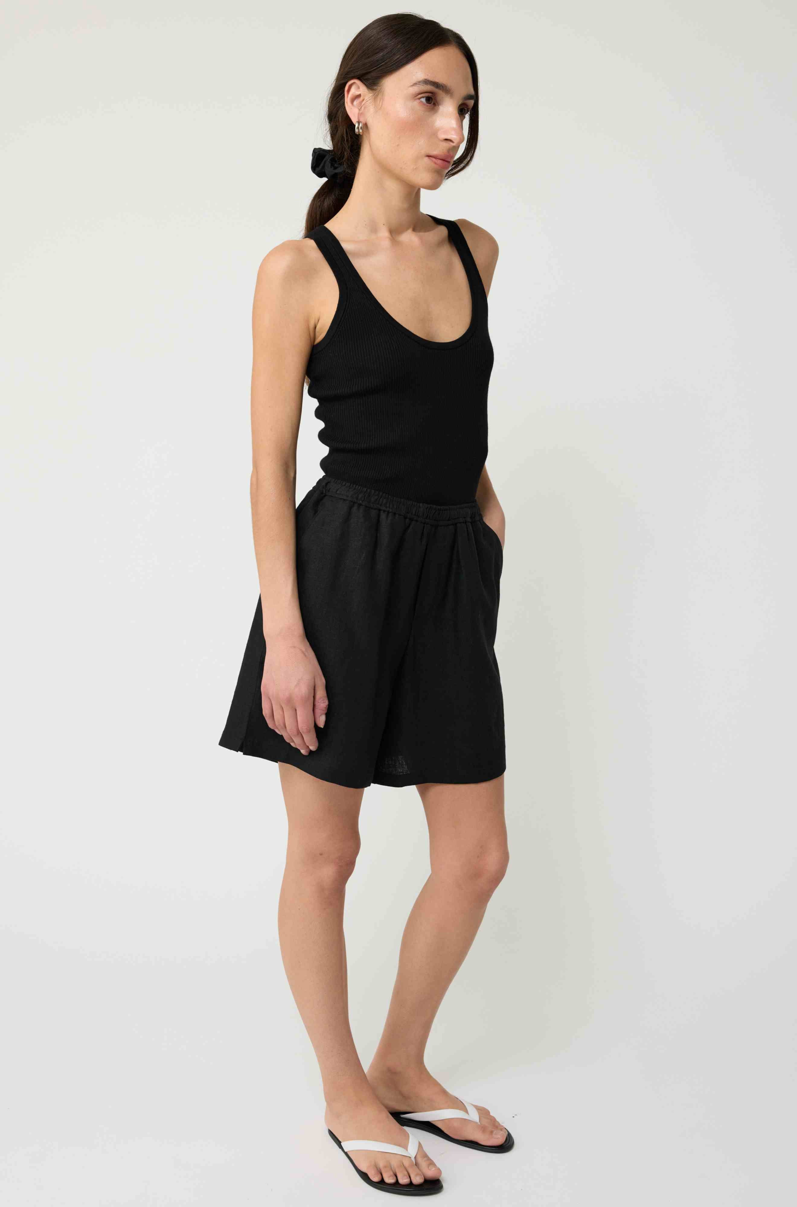 Woman wearing a black tank top and black linen shorts