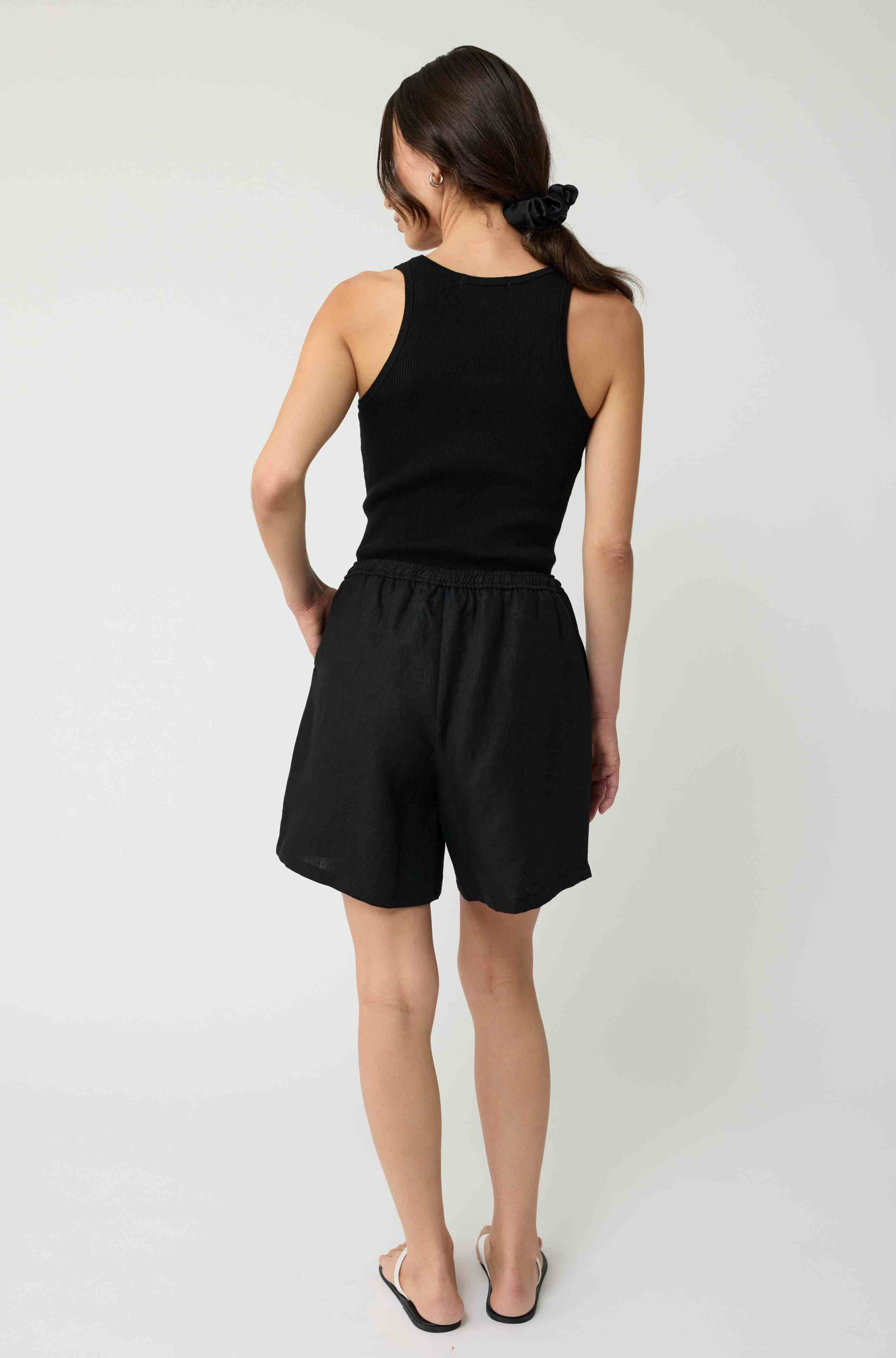 Woman wearing a black tank top and black linen shorts