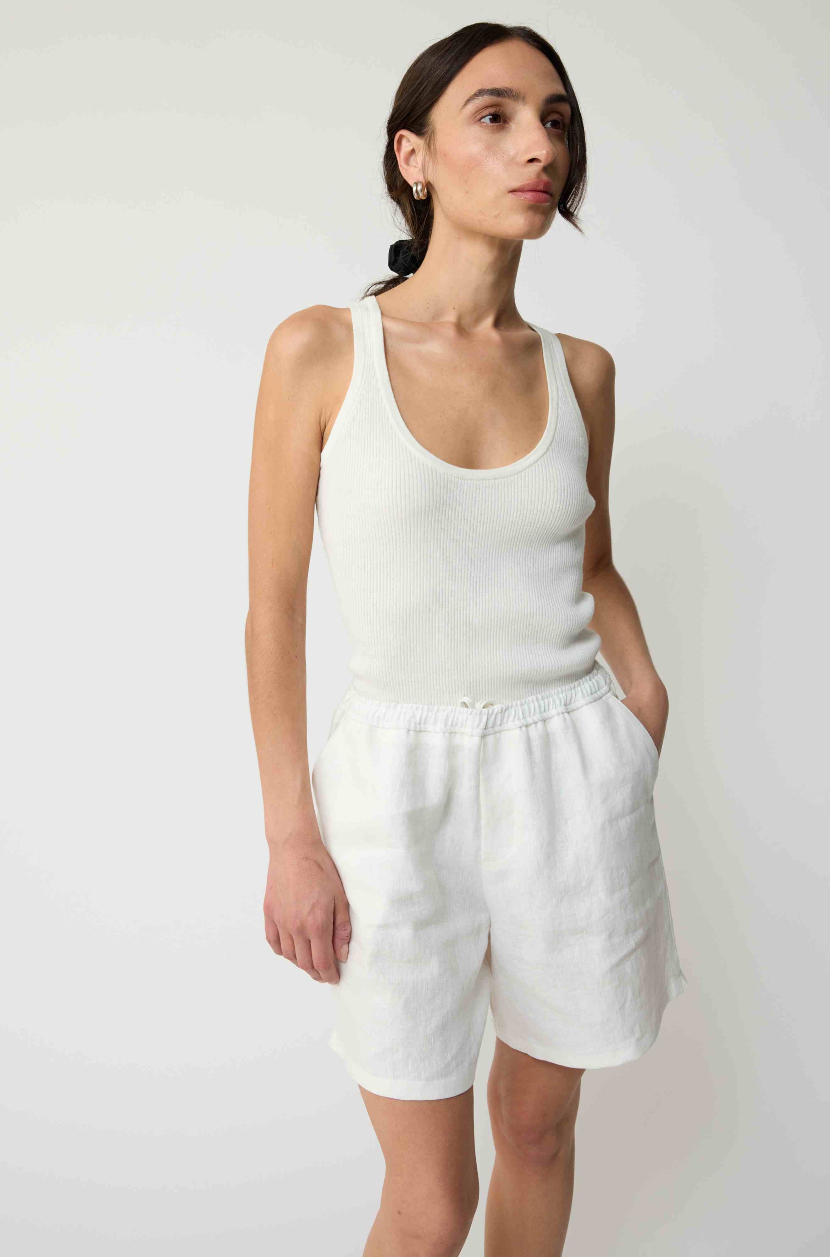 Woman wearing white linen shorts and a white tank top