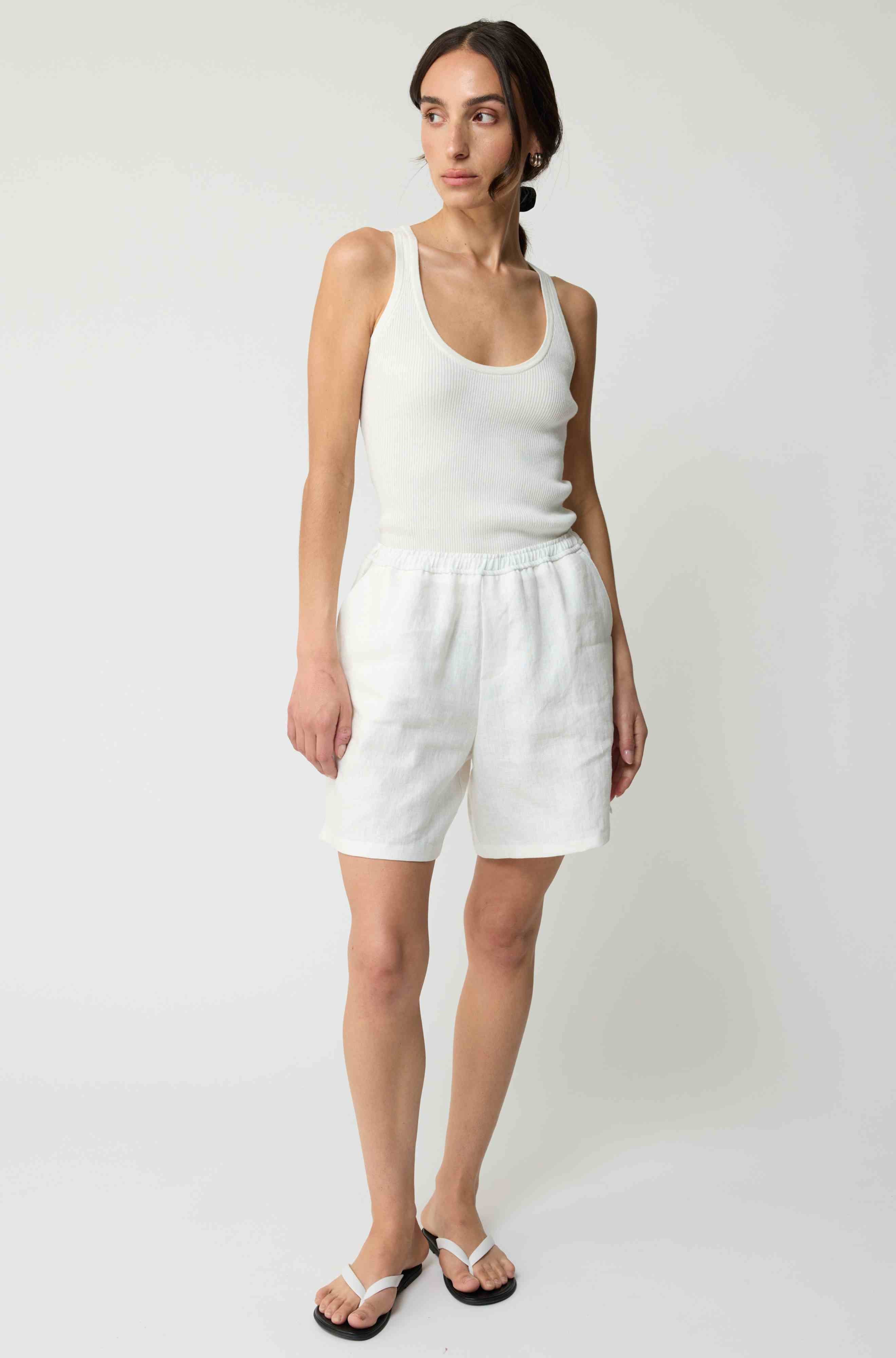 Woman wearing white linen shorts and a white tank top