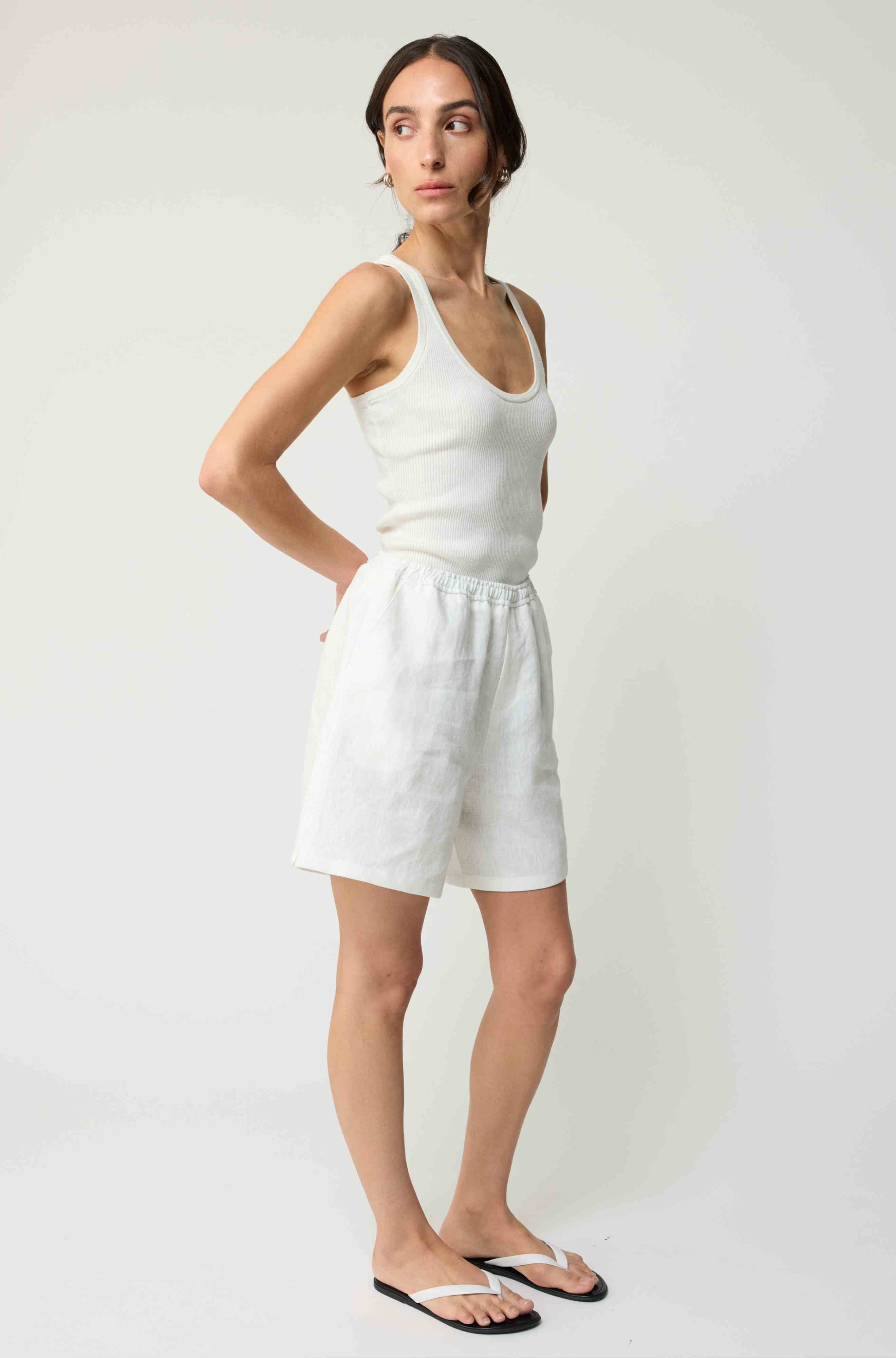 Woman wearing white linen shorts and a white tank top