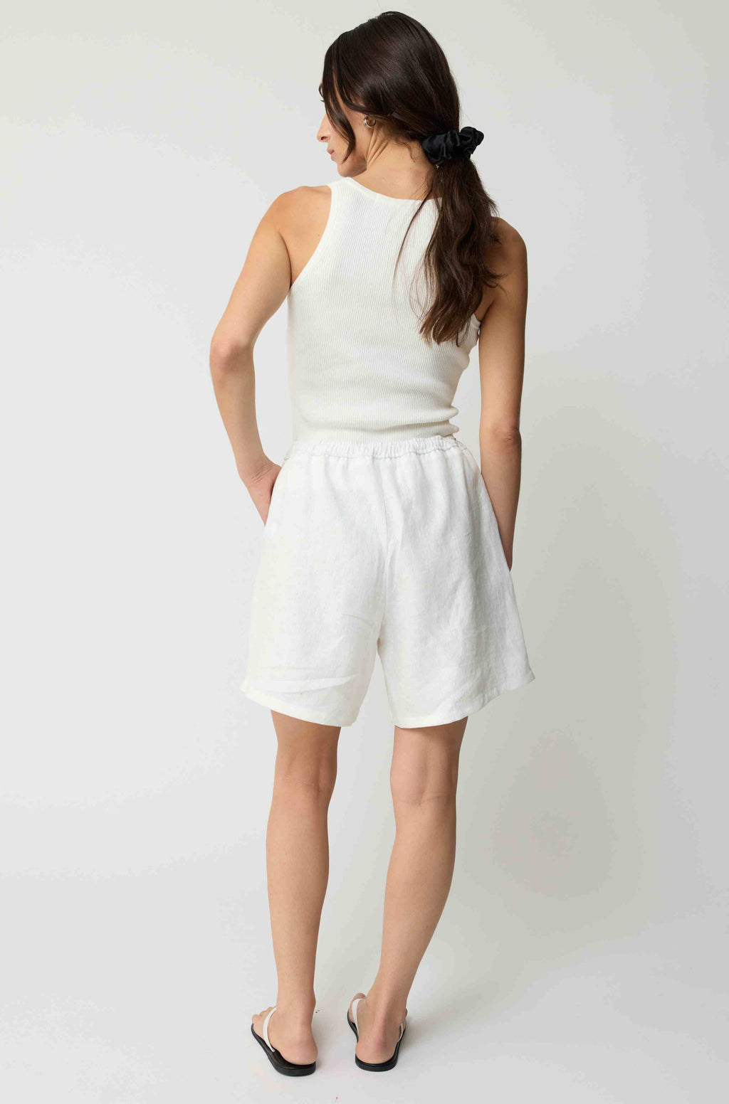 Woman wearing white linen shorts and a white tank top