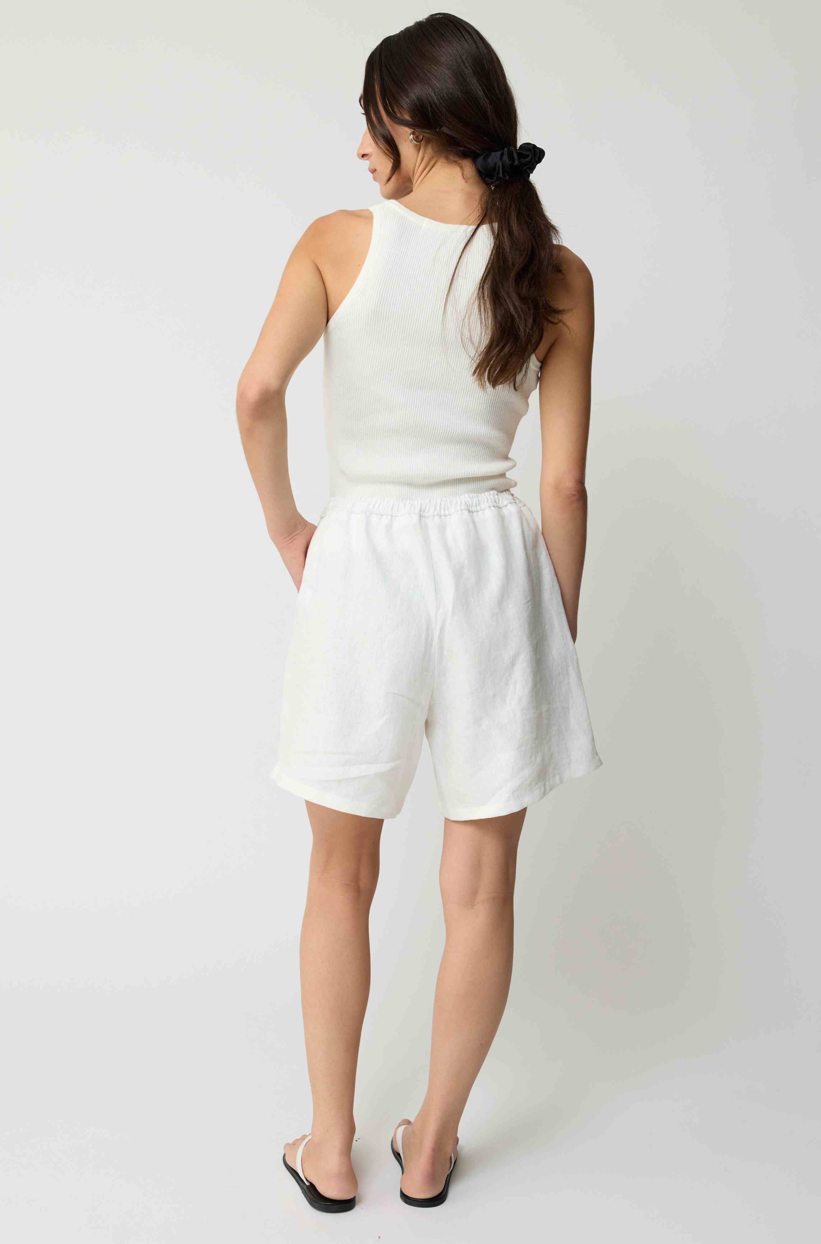Woman wearing white linen shorts and a white tank top