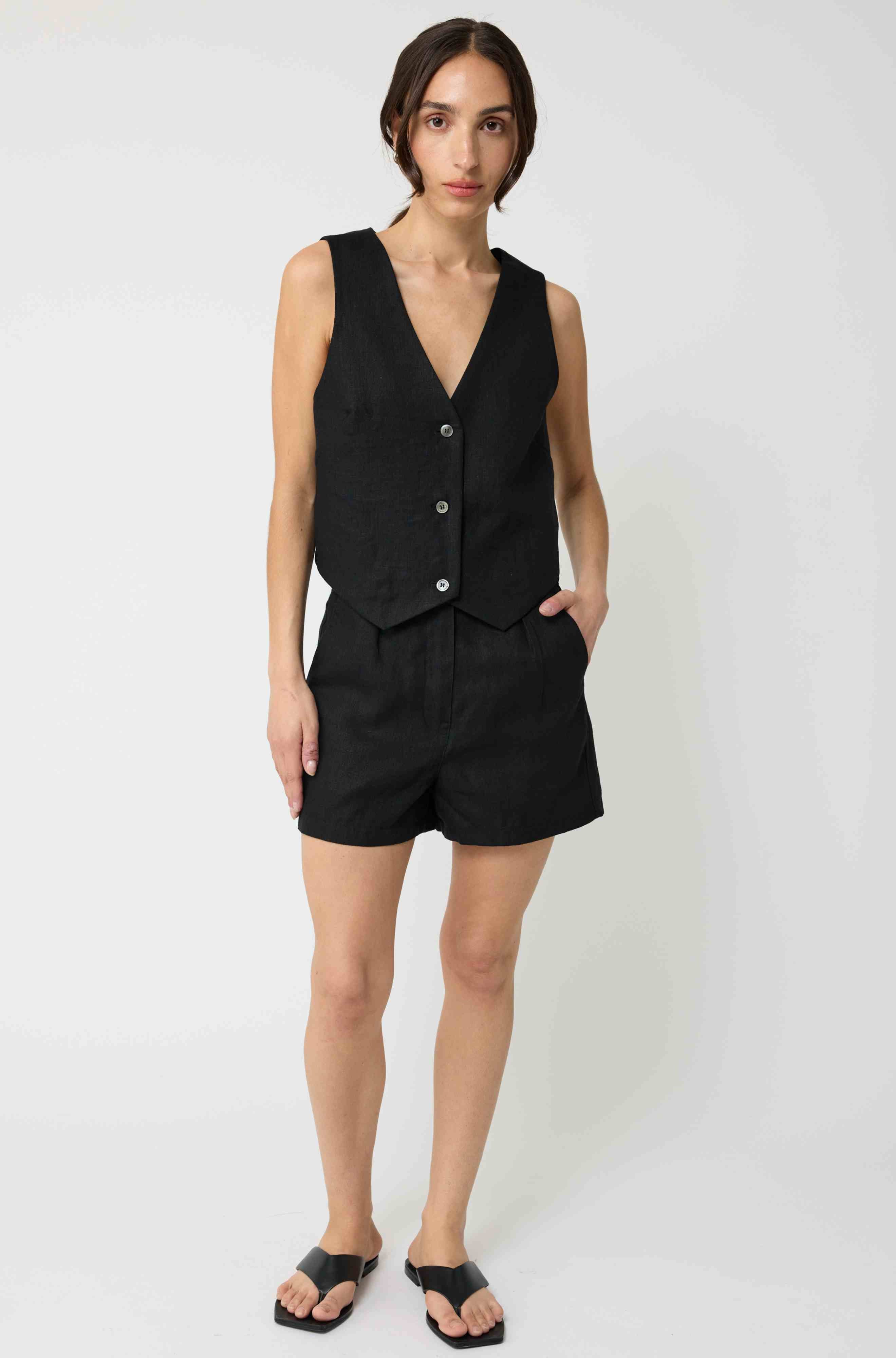 Woman wearing a black linen vest paired with black linen shorts