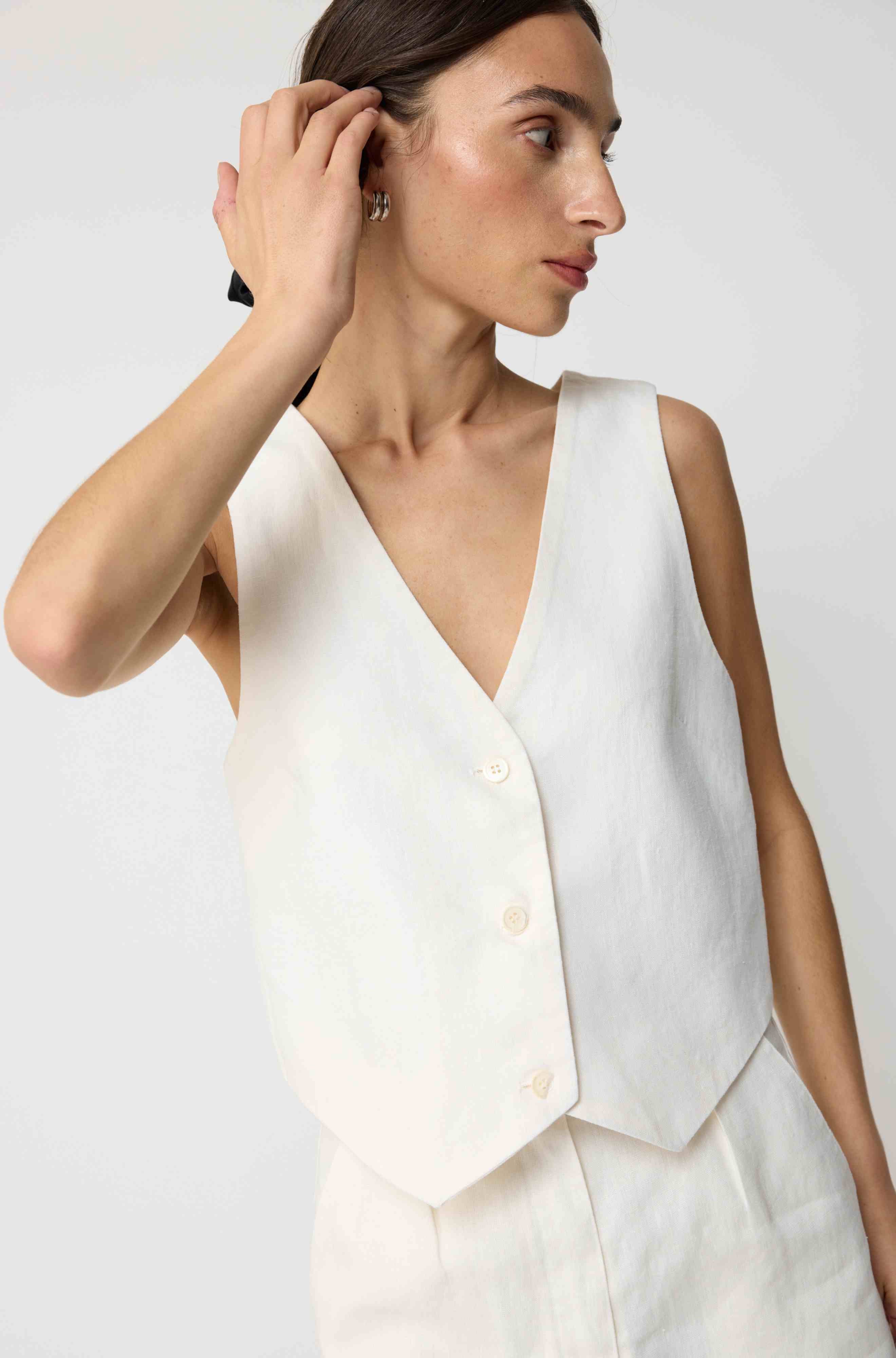 Woman wearing a white linen vest with matching white linen shorts