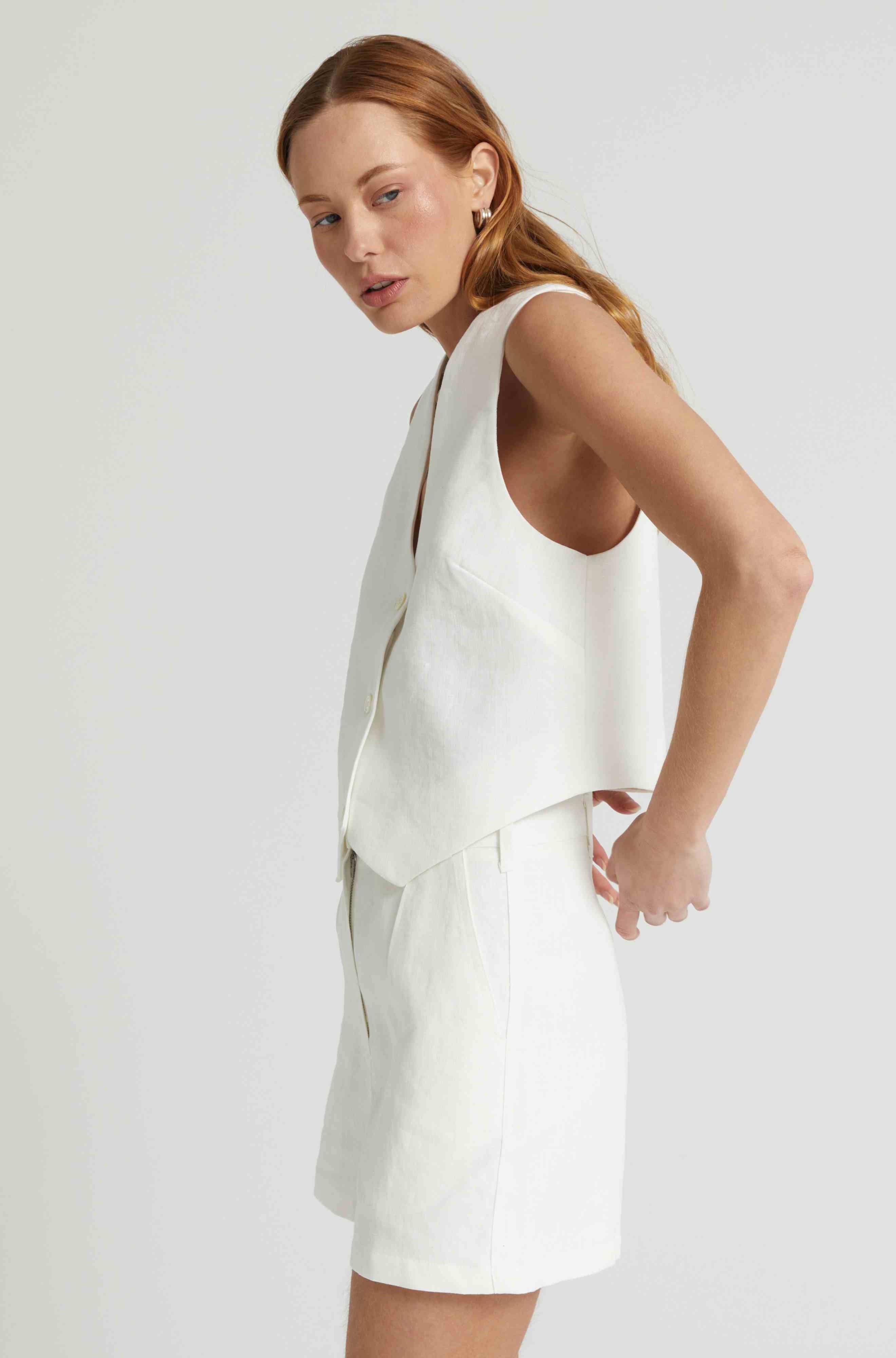 Woman wearing a white linen vest with matching white linen shorts