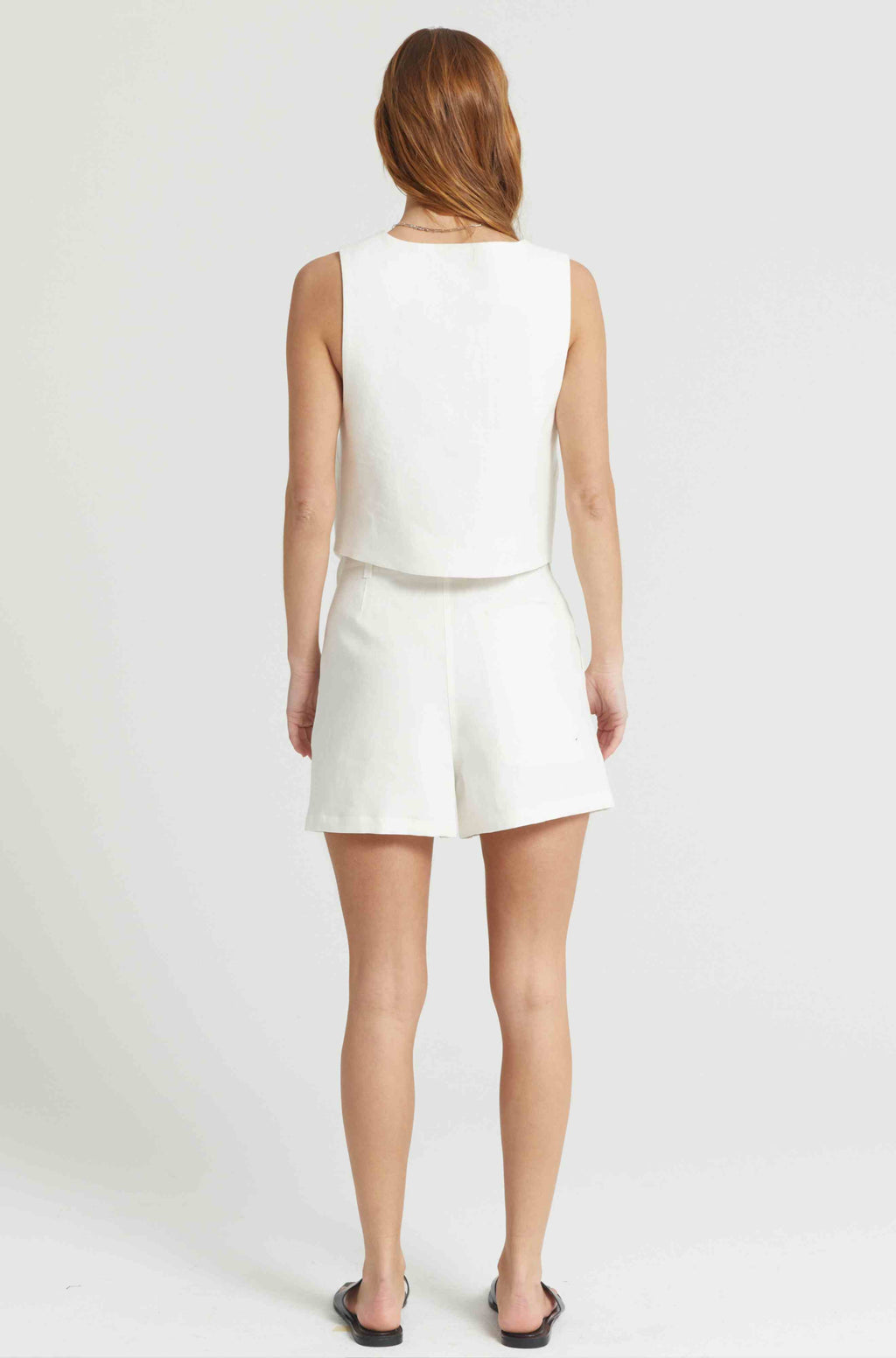 Woman wearing a white linen vest with matching white linen shorts