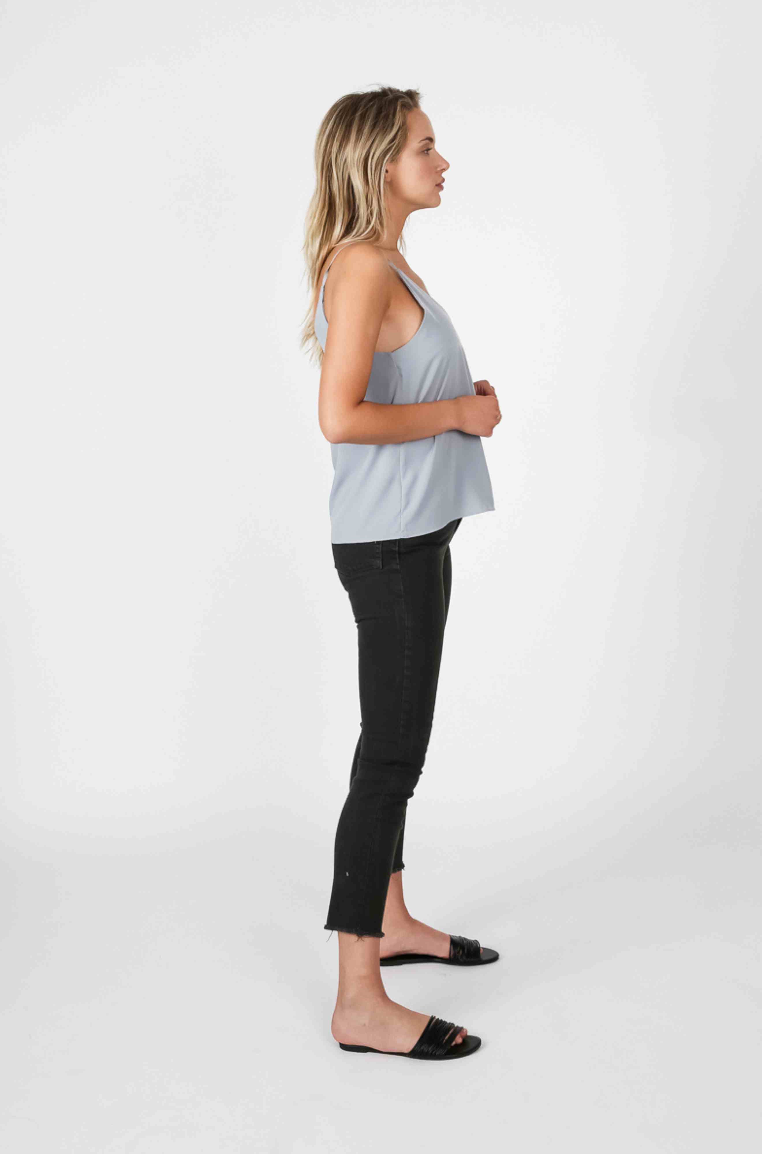 Woman wearing a light blue cami tank top and dark black pants
