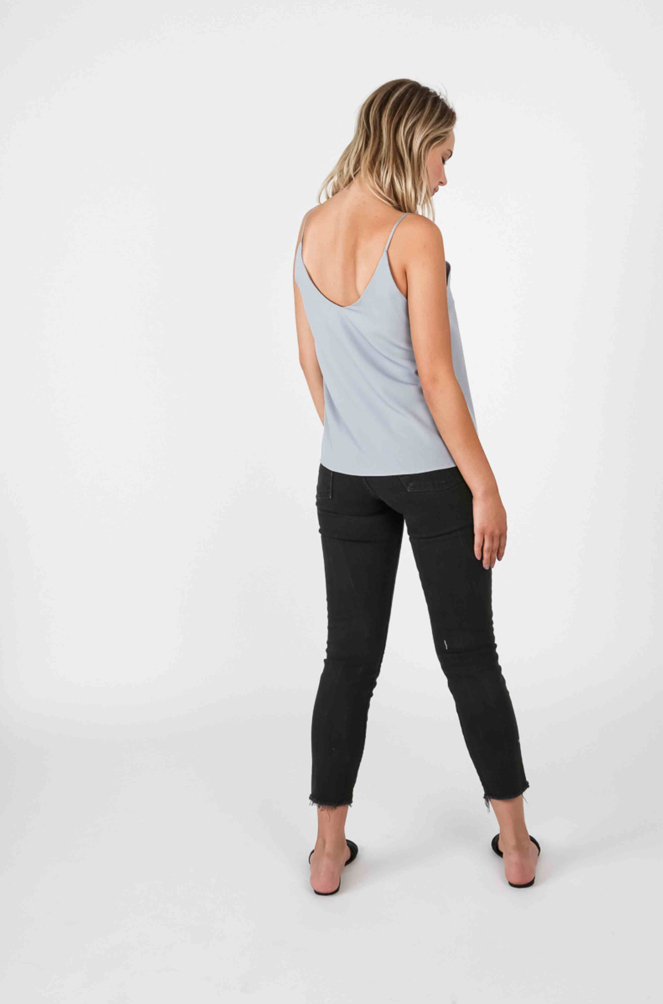 Woman wearing a light blue cami tank top and dark black pants