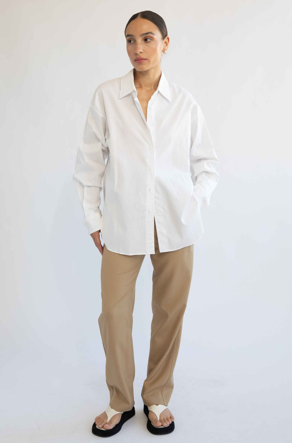 Woman wearing a white shirt and beige pants on a white background