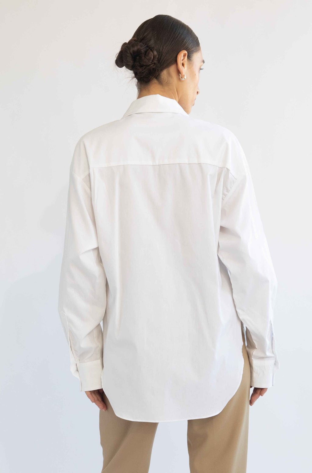 Person wearing a white shirt and beige pants against a white background