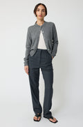 Person wearing a gray cardigan and dark pants on a white background