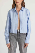 Person wearing a light blue button-up shirt and gray jeans on a white background