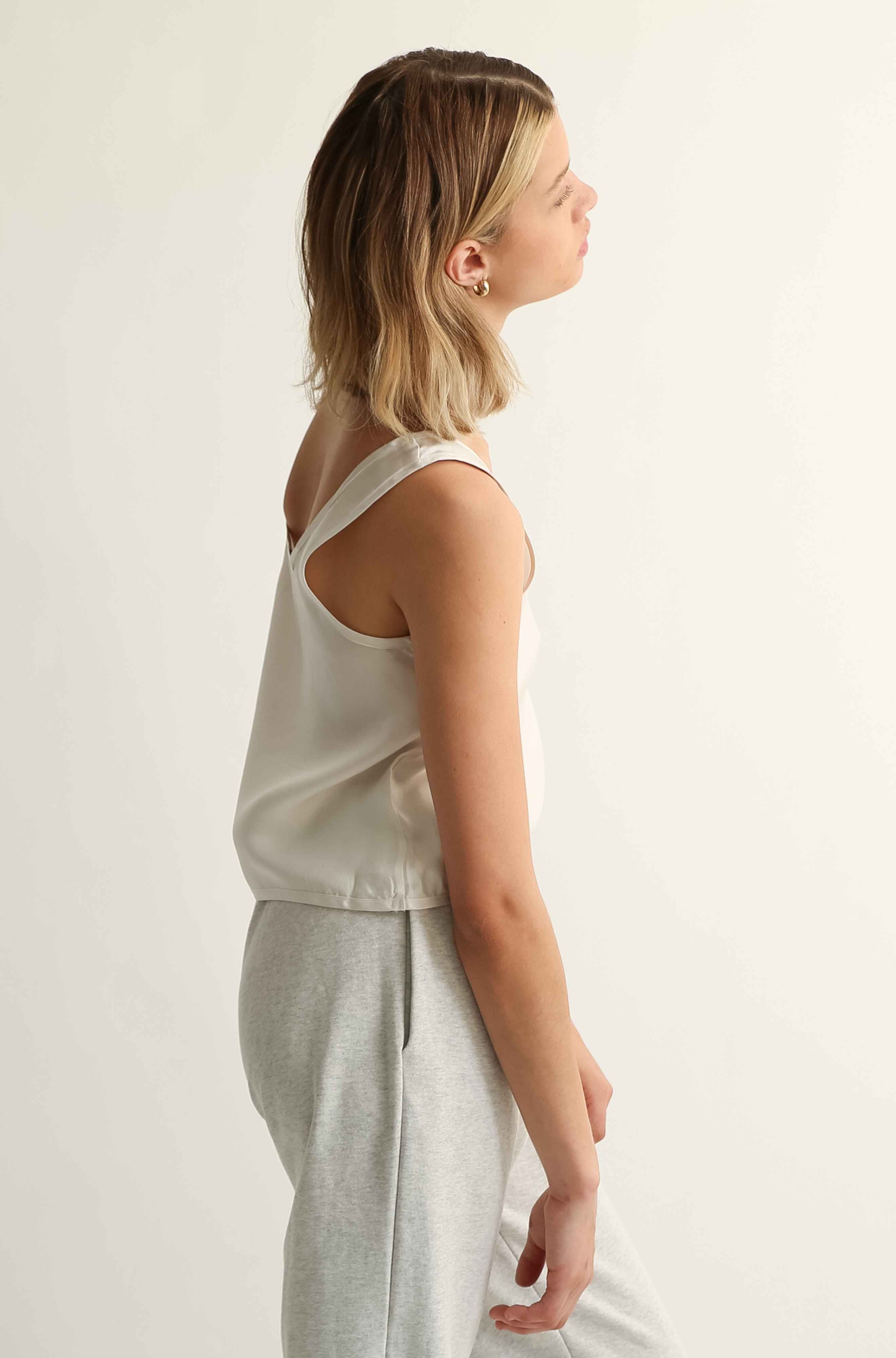 Woman wearing a sleeveless top on a light grey background