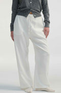 Woman wearing white linen pants on a light grey background