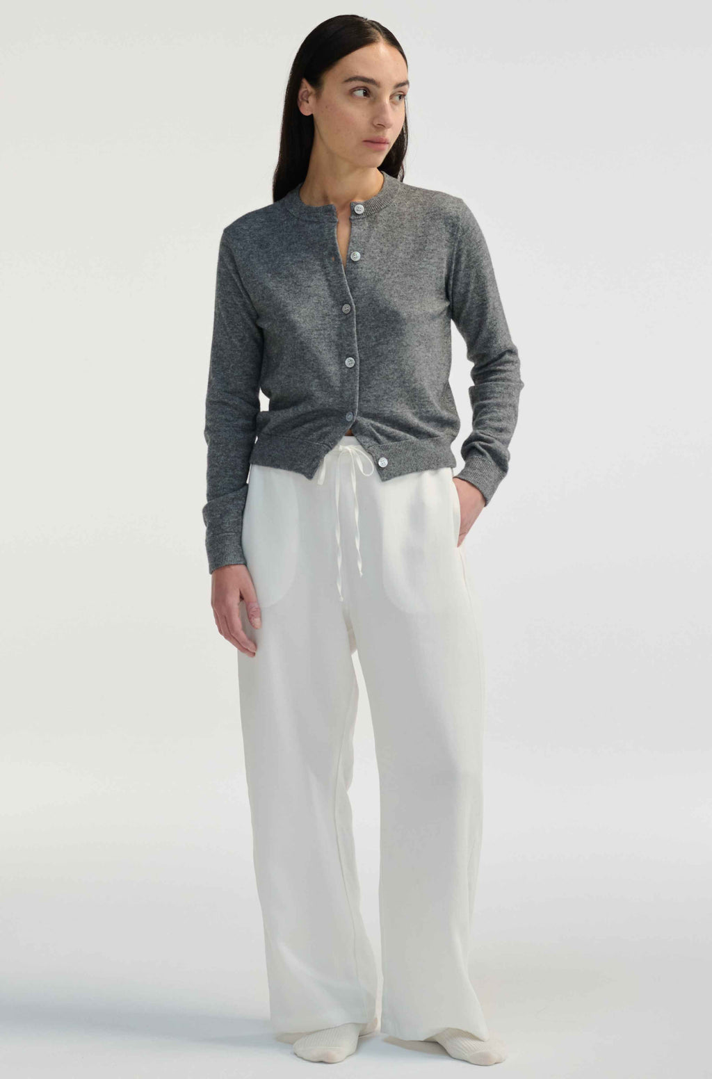Woman wearing white linen pants on a light grey background