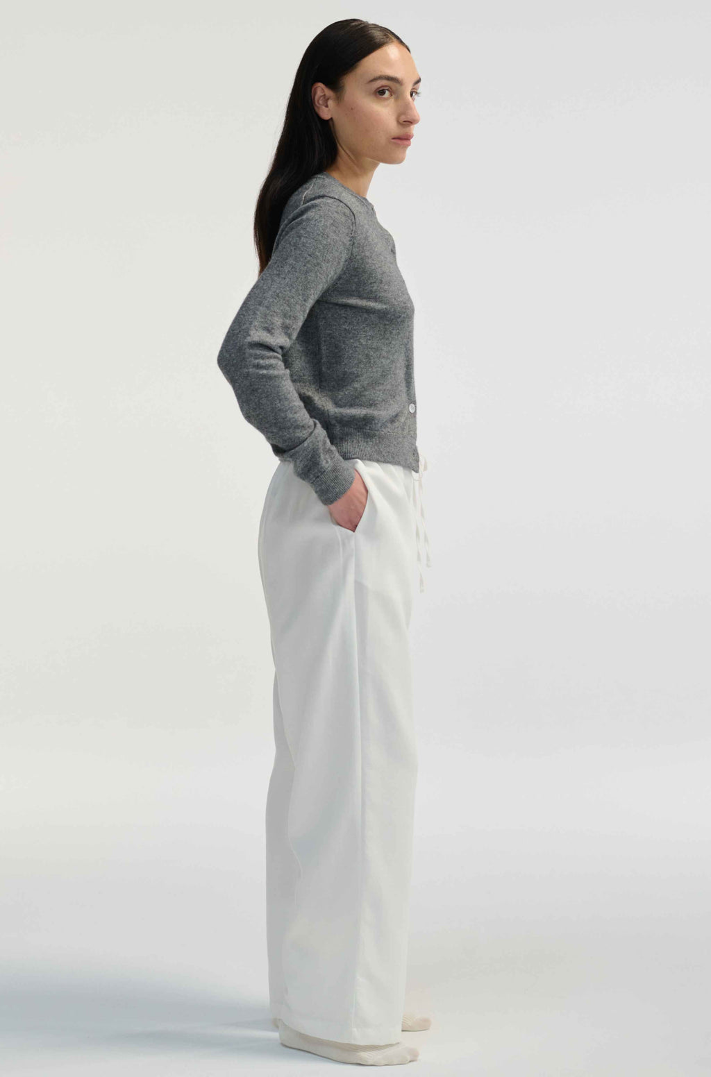 Woman wearing white linen pants on a light grey background