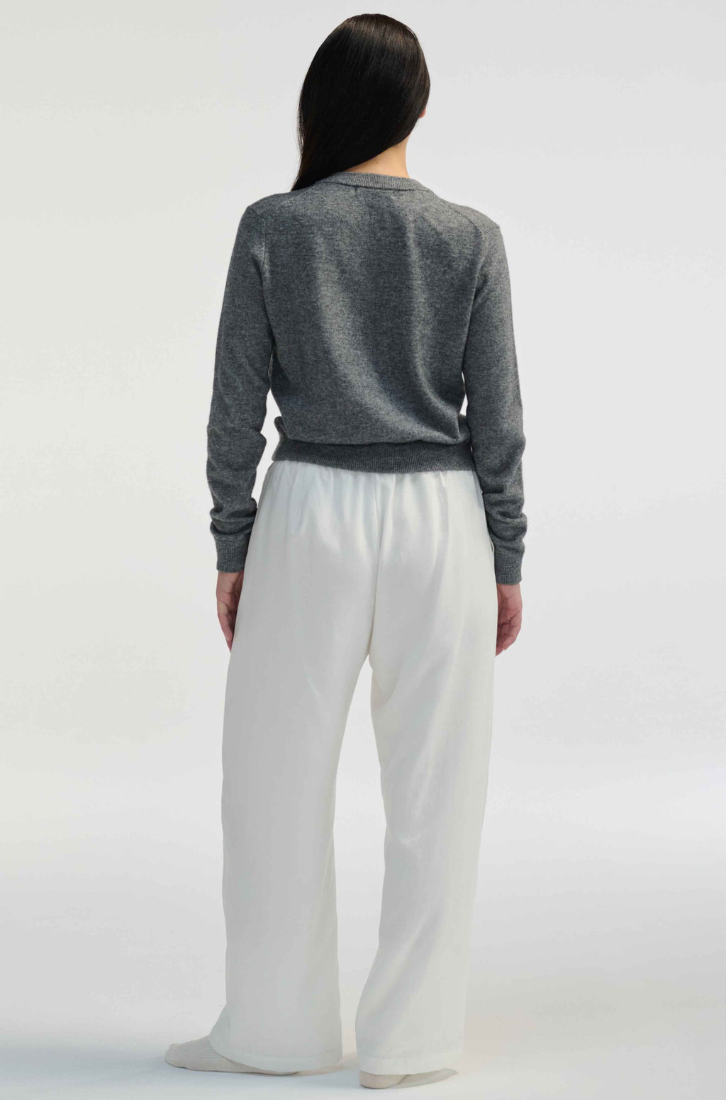 Woman wearing white linen pants on a light grey background