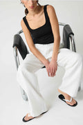 Woman wearing a black square tank top and white linen pants
