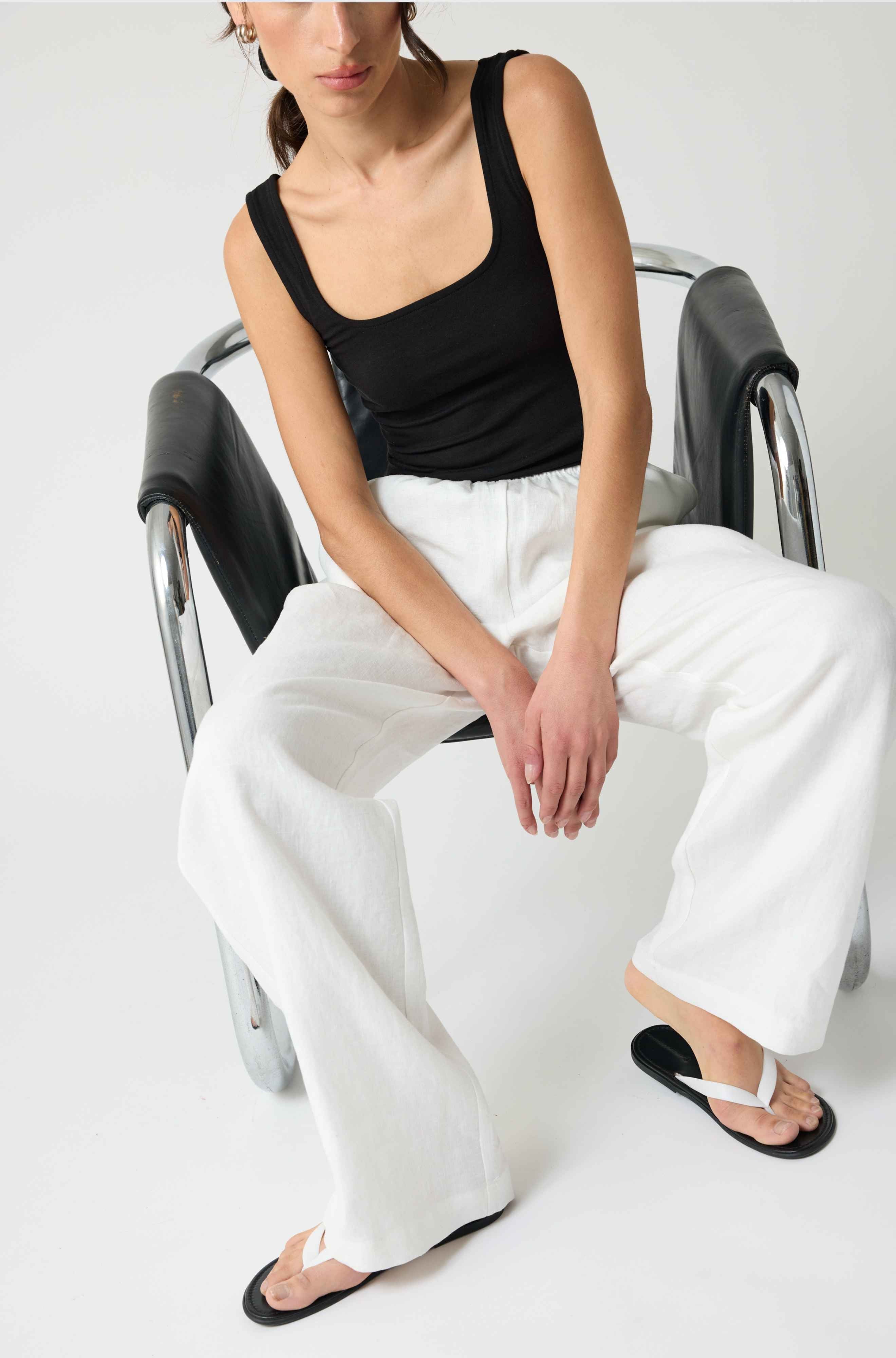 Woman wearing a black square tank top and white linen pants