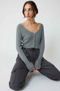 Woman wearing a grey cardigan with grey cargo pants on a light grey background