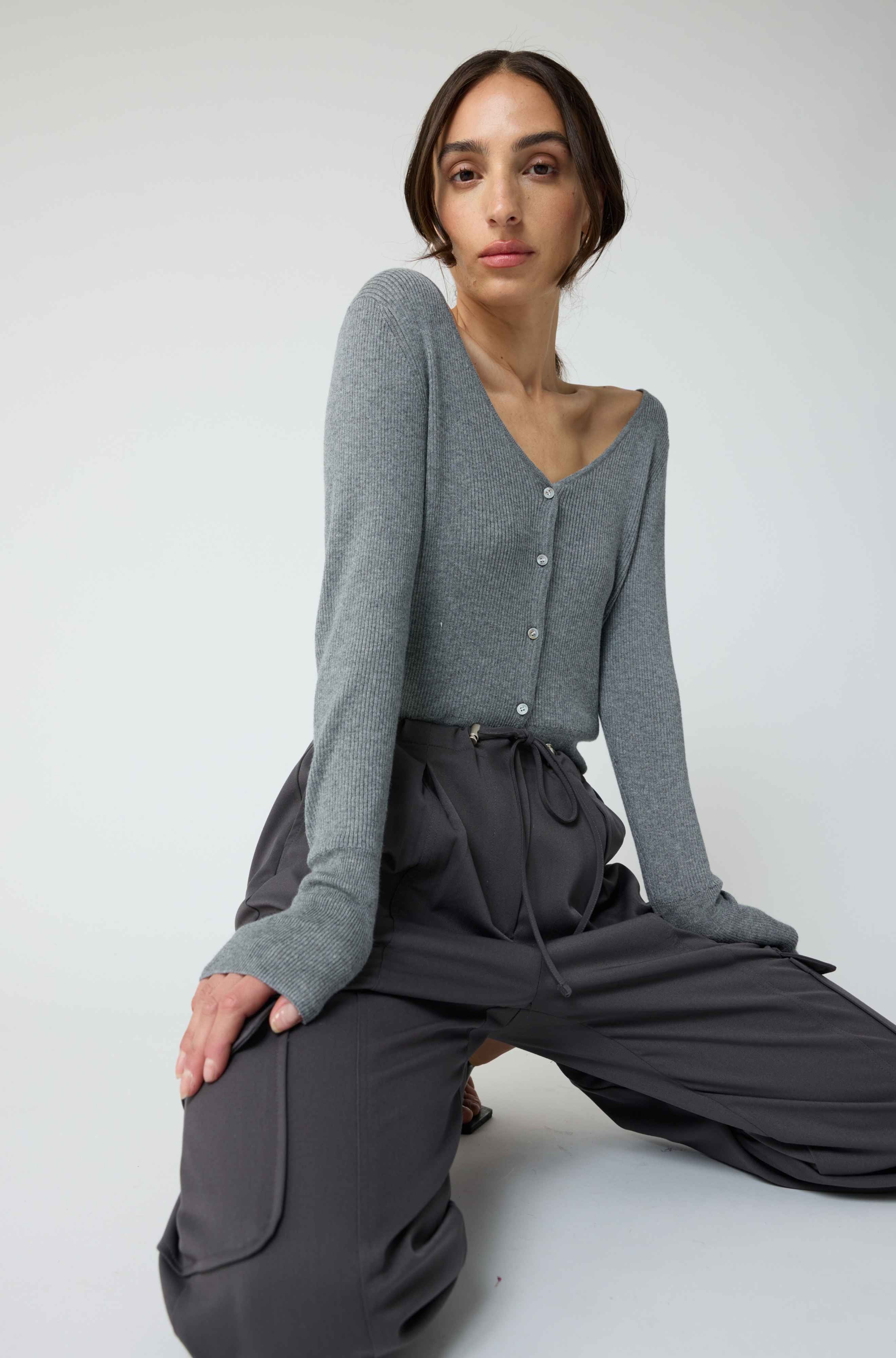 Woman wearing a grey cardigan with grey cargo pants on a light grey background