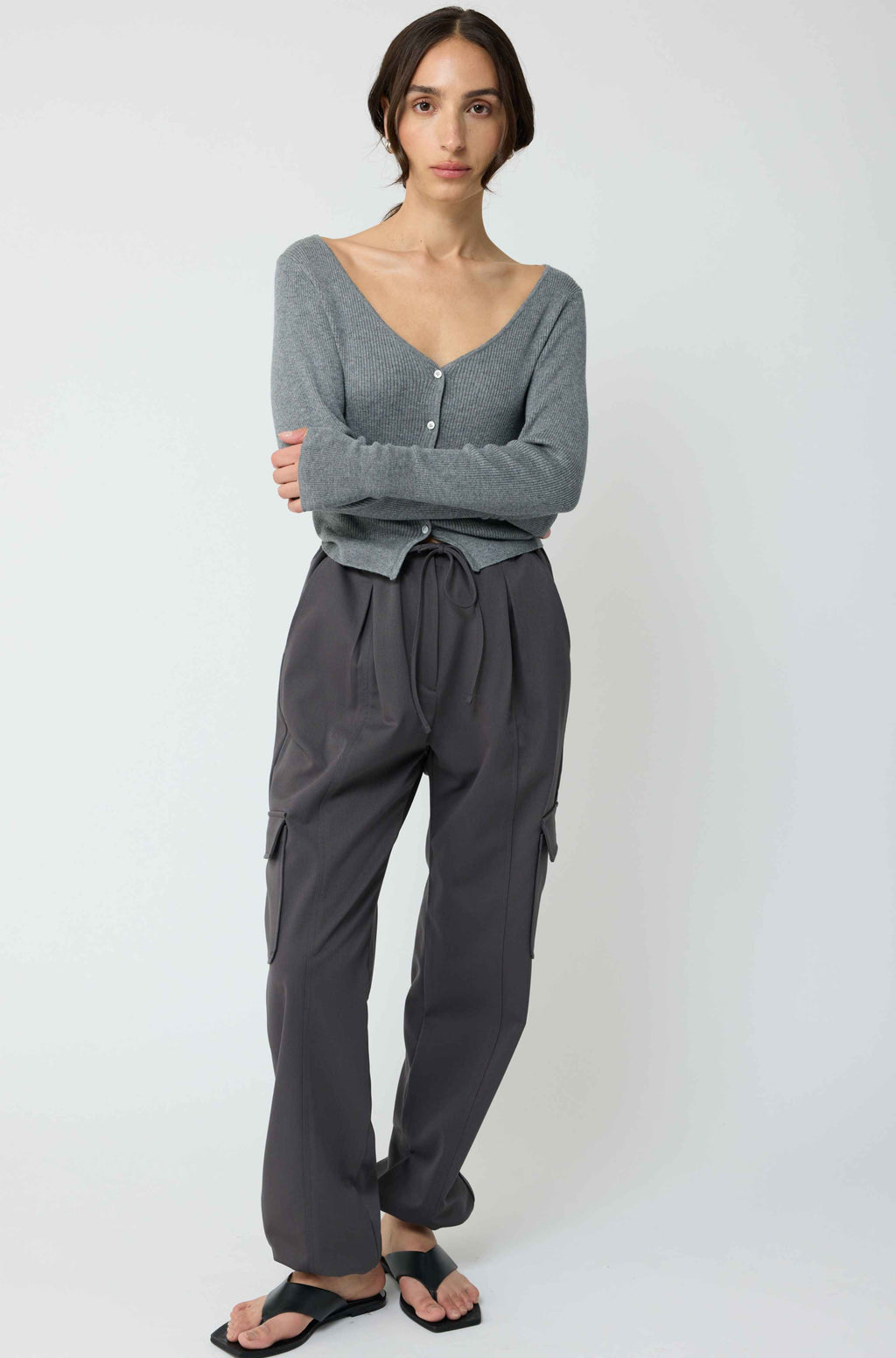 Woman wearing a grey cardigan with grey cargo pants on a light grey background
