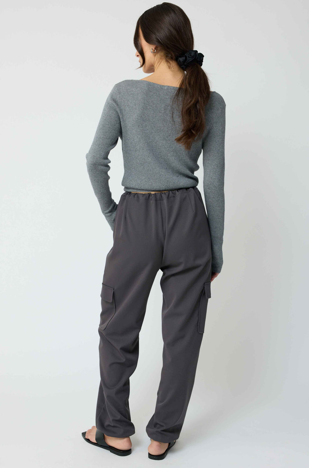 Woman wearing a grey cardigan with grey cargo pants on a light grey background