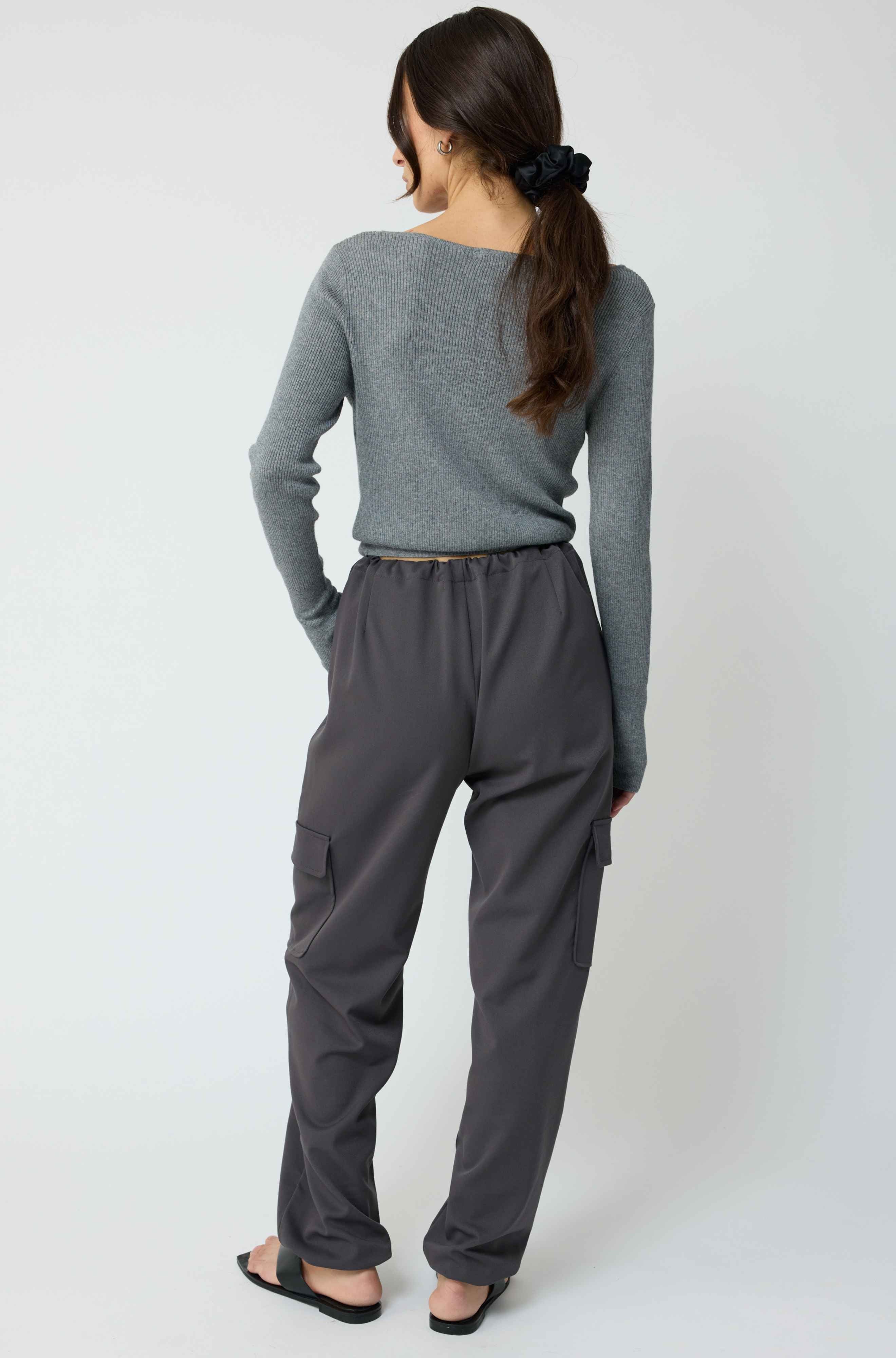 Woman wearing a grey cardigan with grey cargo pants on a light grey background