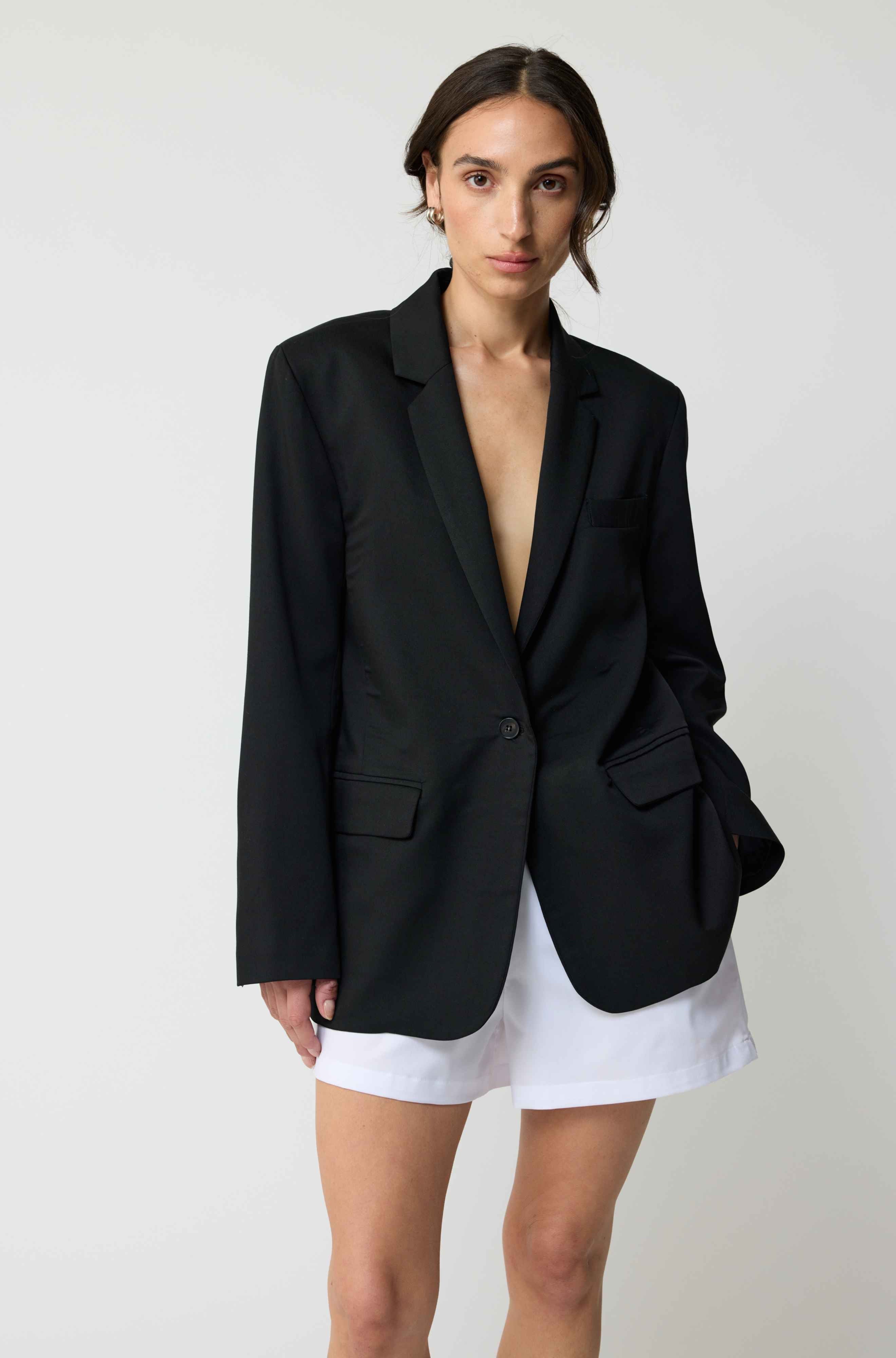 Woman wearing a black blazer over a white top with a plain background