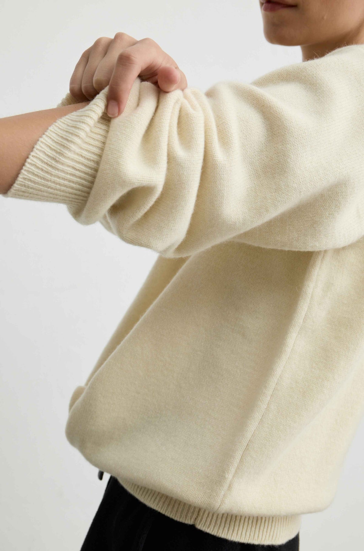 A close-up of a person wearing a yellow knit sweater, showing the soft texture of the fabric and the ribbed cuff.