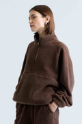 Person wearing a brown fleece pullover against a light gray background