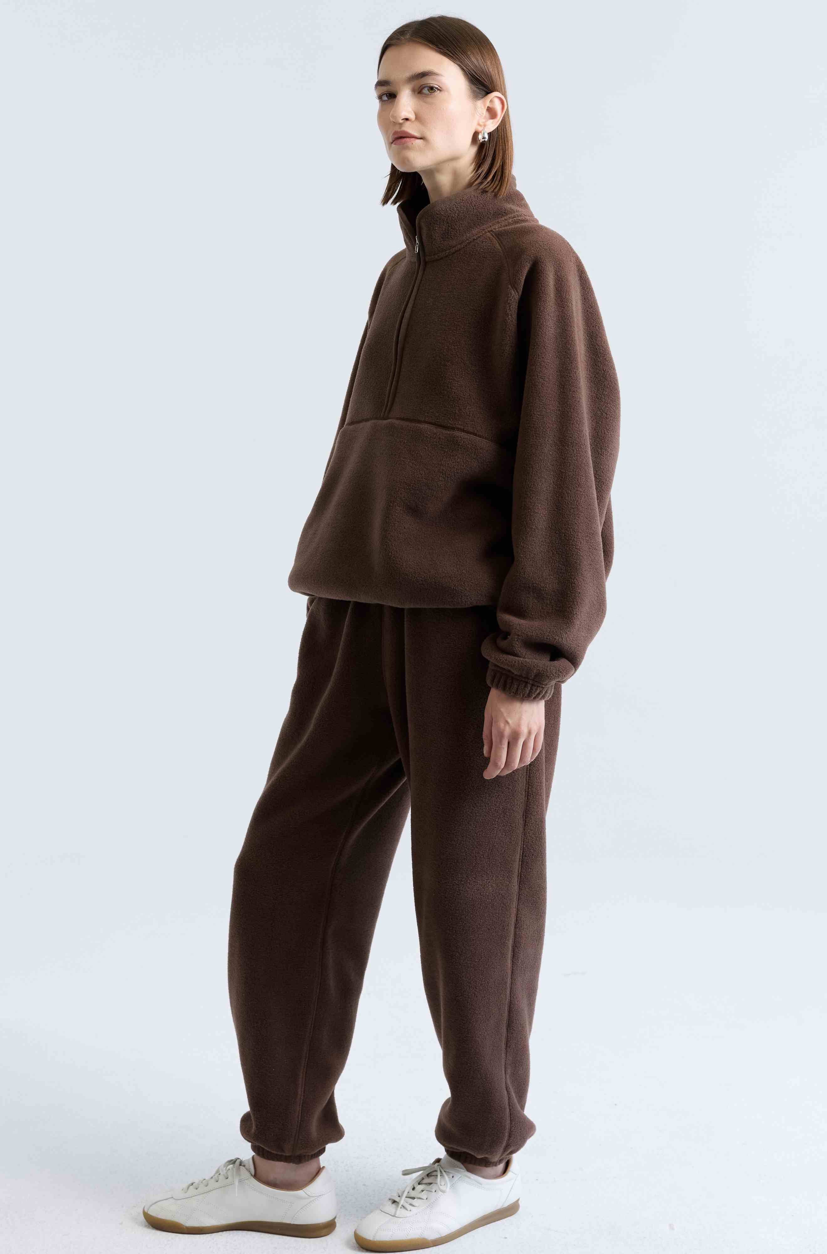 Person wearing a brown tracksuit on a white background