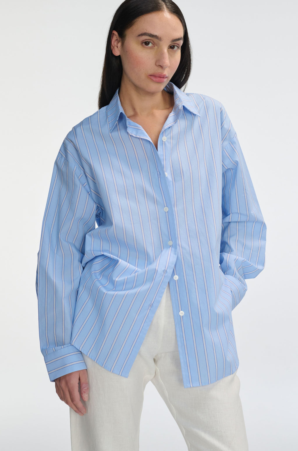 Woman wearing a light blue striped shirt on a white background
