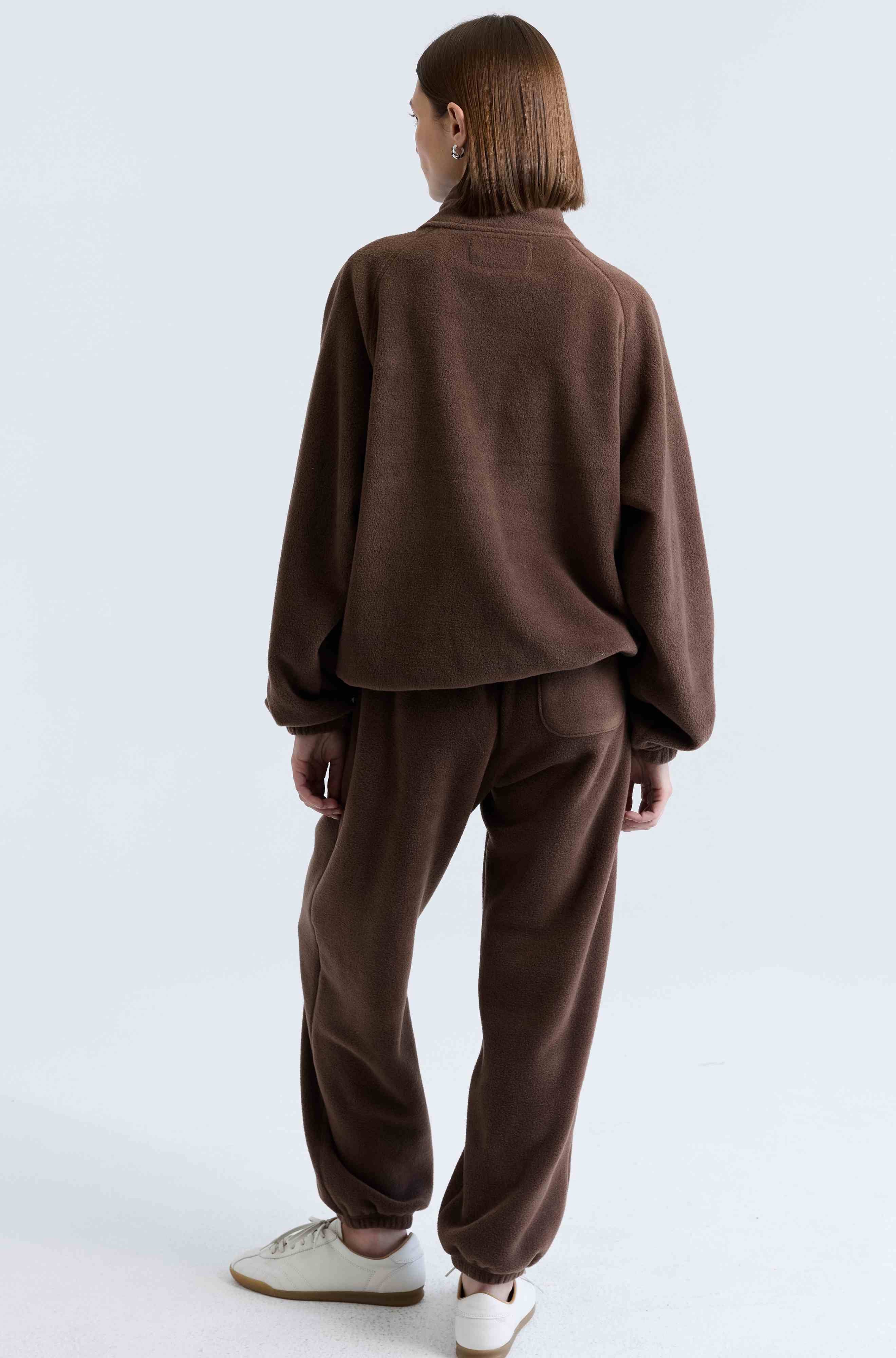 Person wearing a brown tracksuit on a light gray background