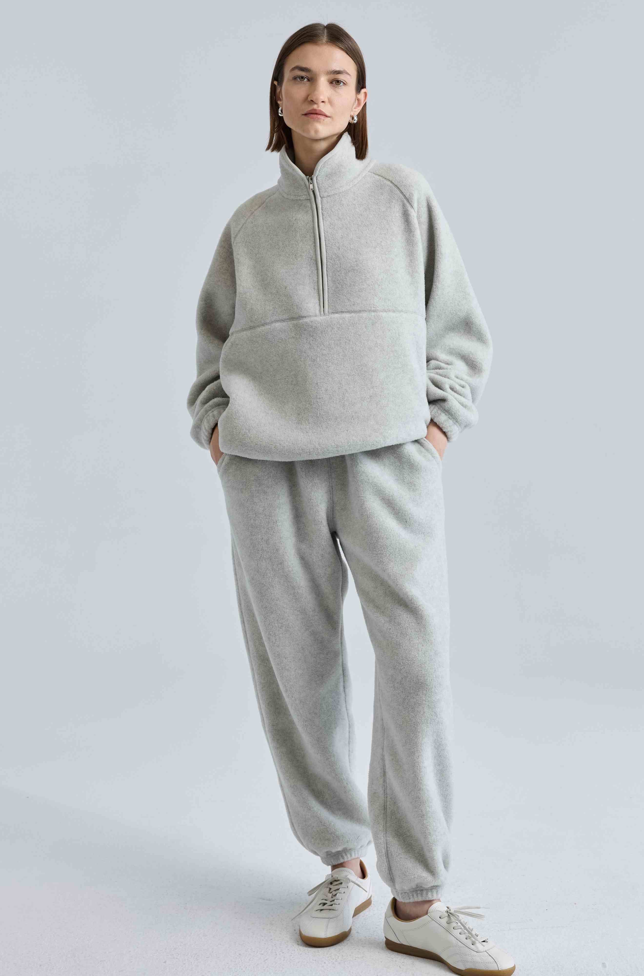 Person wearing a gray tracksuit on a light gray background