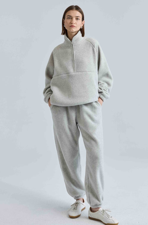 Person wearing a gray tracksuit on a light gray background