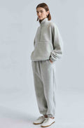 Person wearing a gray tracksuit on a light gray background