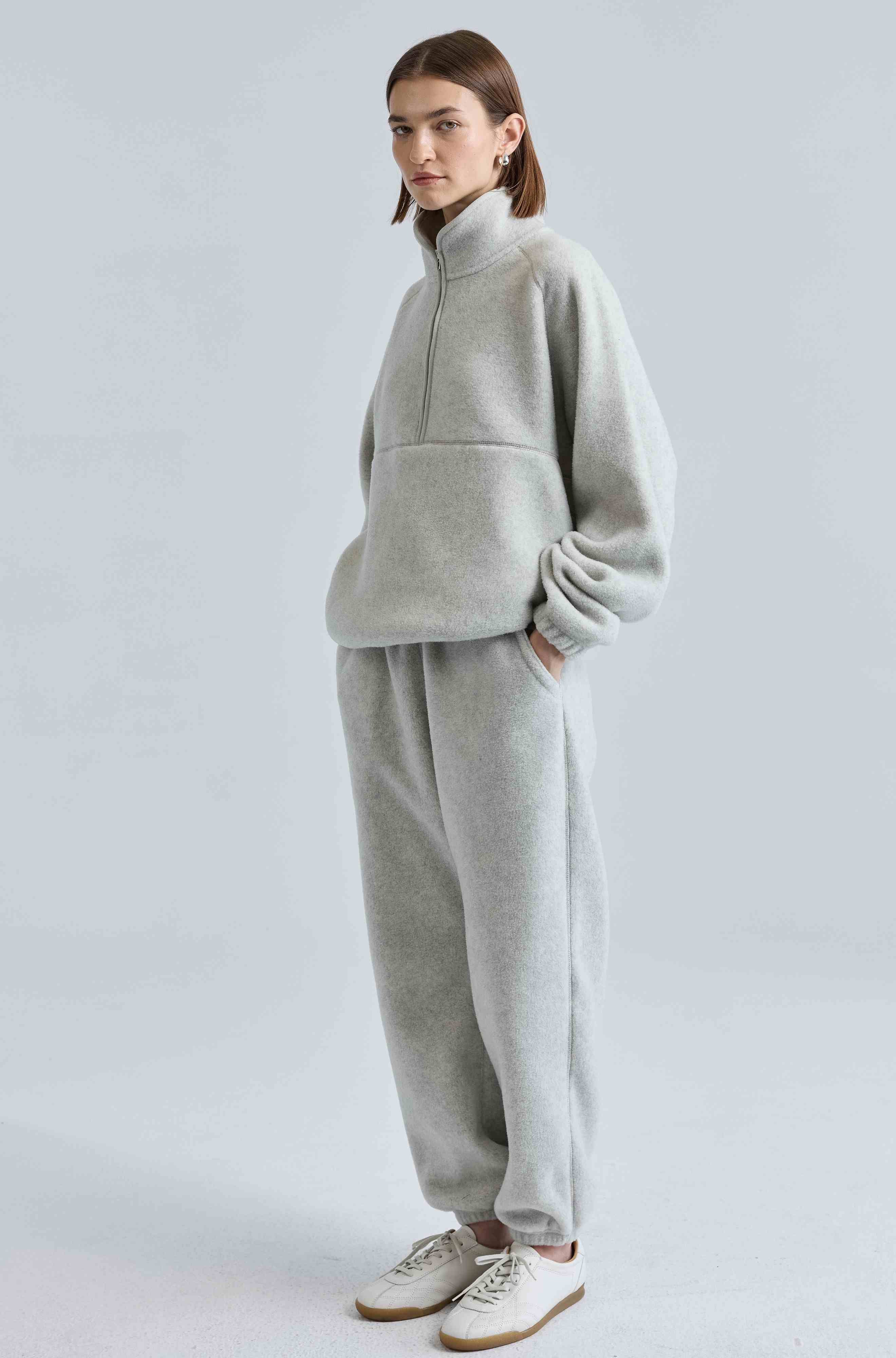 Person wearing a gray tracksuit on a light gray background