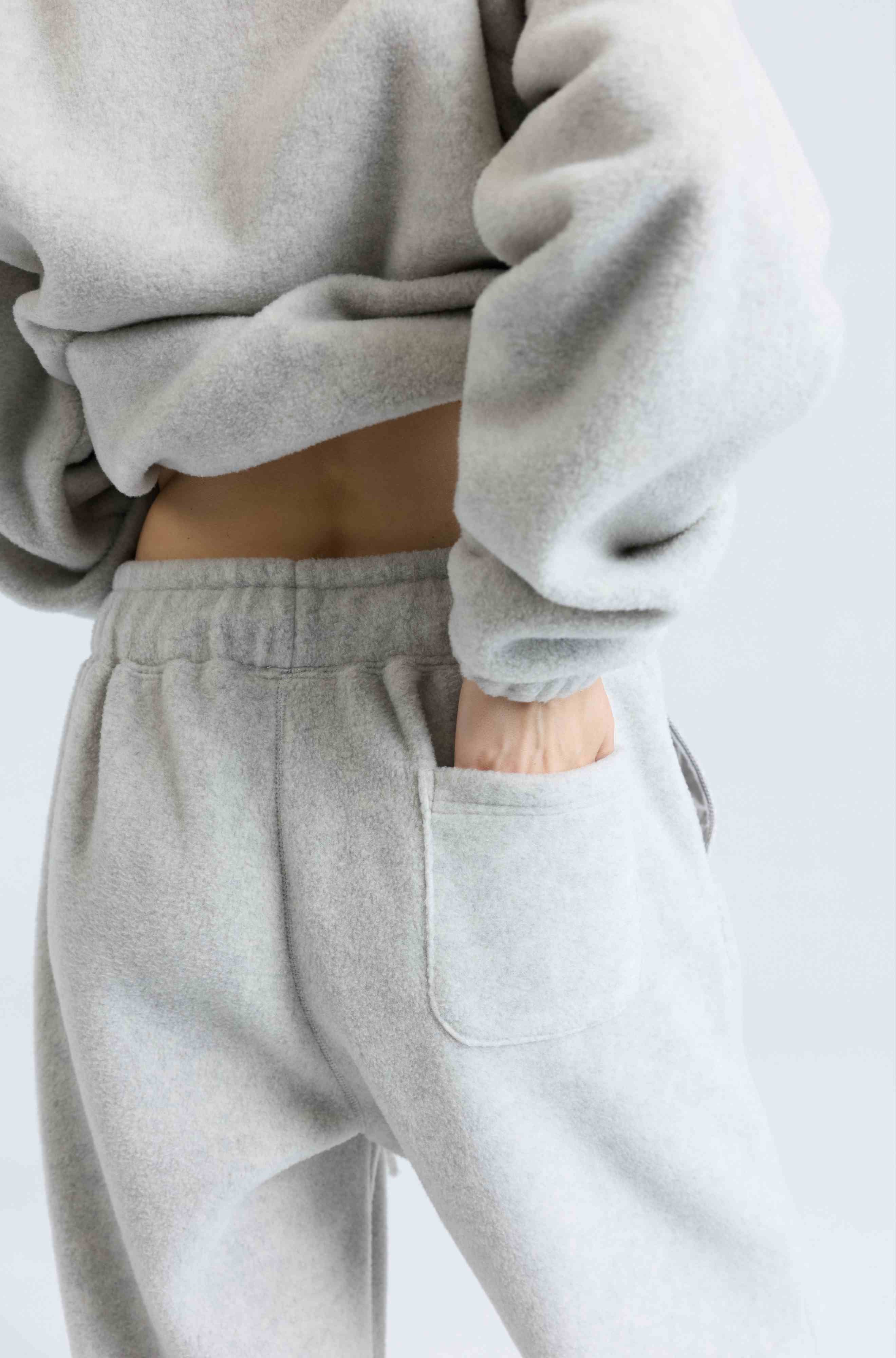 Person wearing a gray sweatshirt and pants on a light background