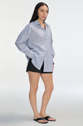 Woman wearing a light blue striped shirt and black shorts on a white background