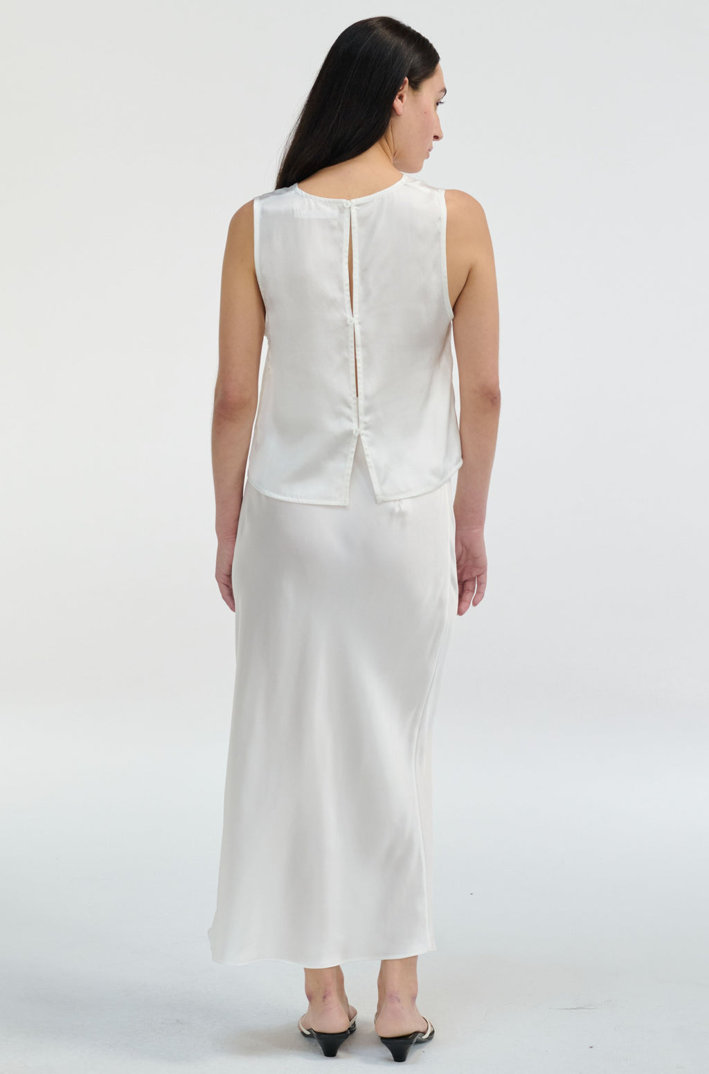 Woman wearing a white silk sleeveless top and skirt set on a white background